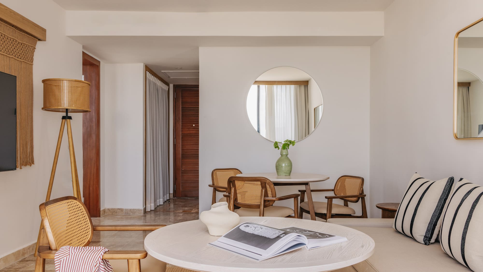 Resort suite living room with light wood and cane furniture, sofa, round tables.