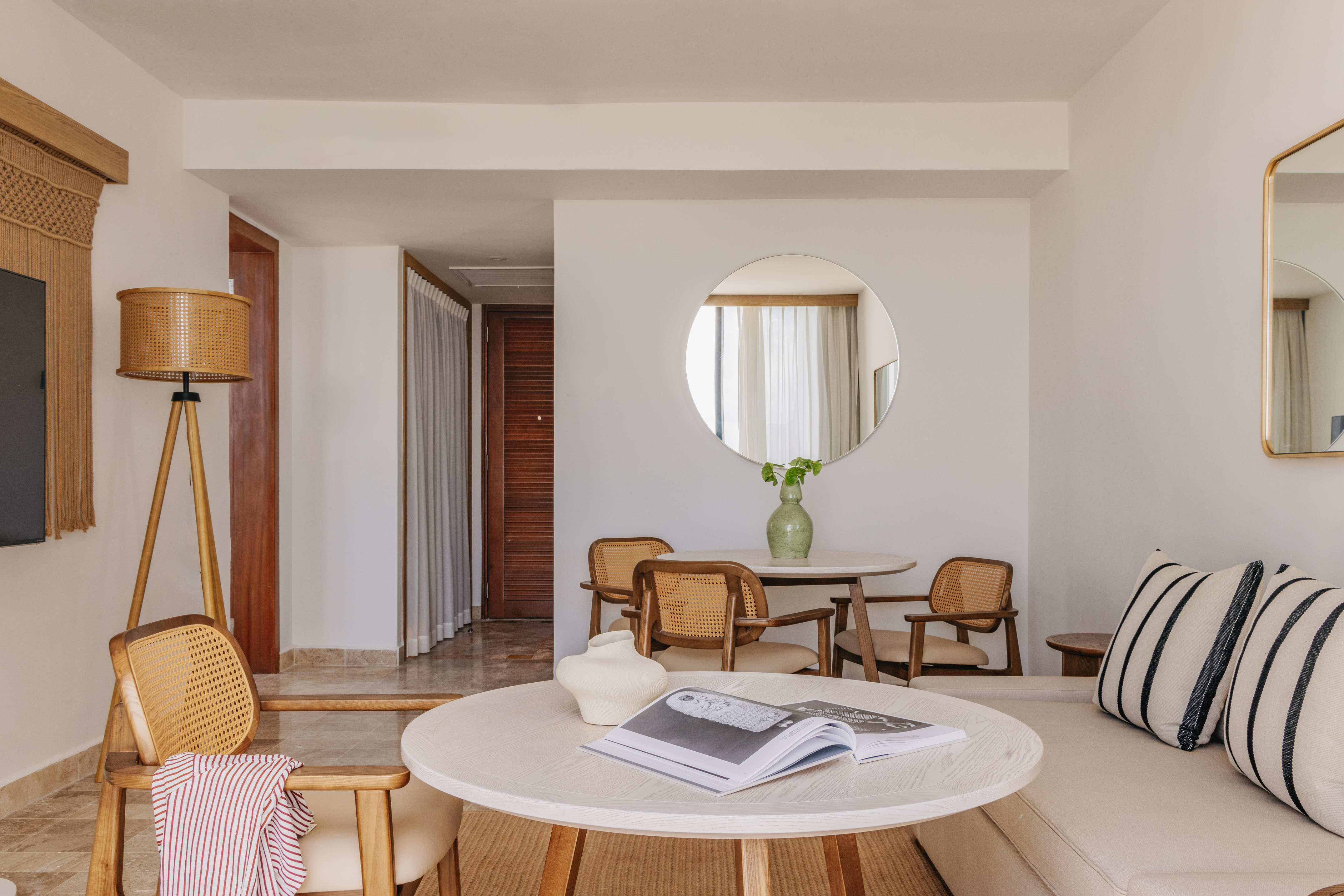 Resort suite living room with light wood and cane furniture, sofa, round tables.