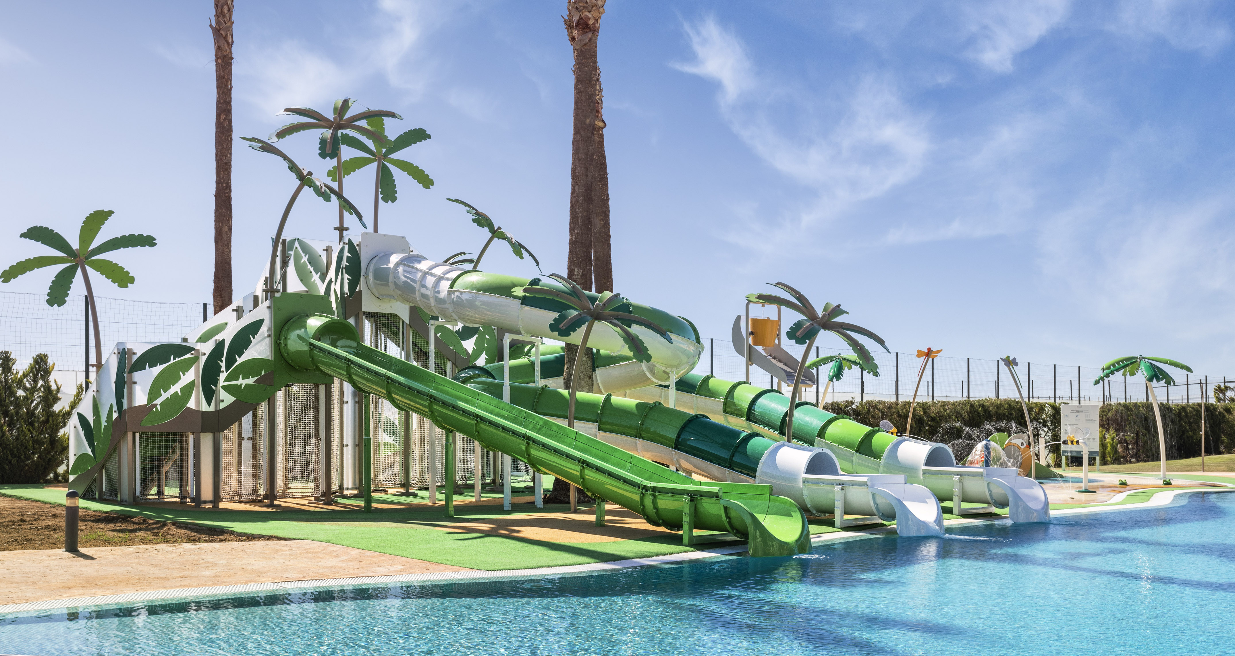Sunny resort water park with green slides, palm trees, and pool.