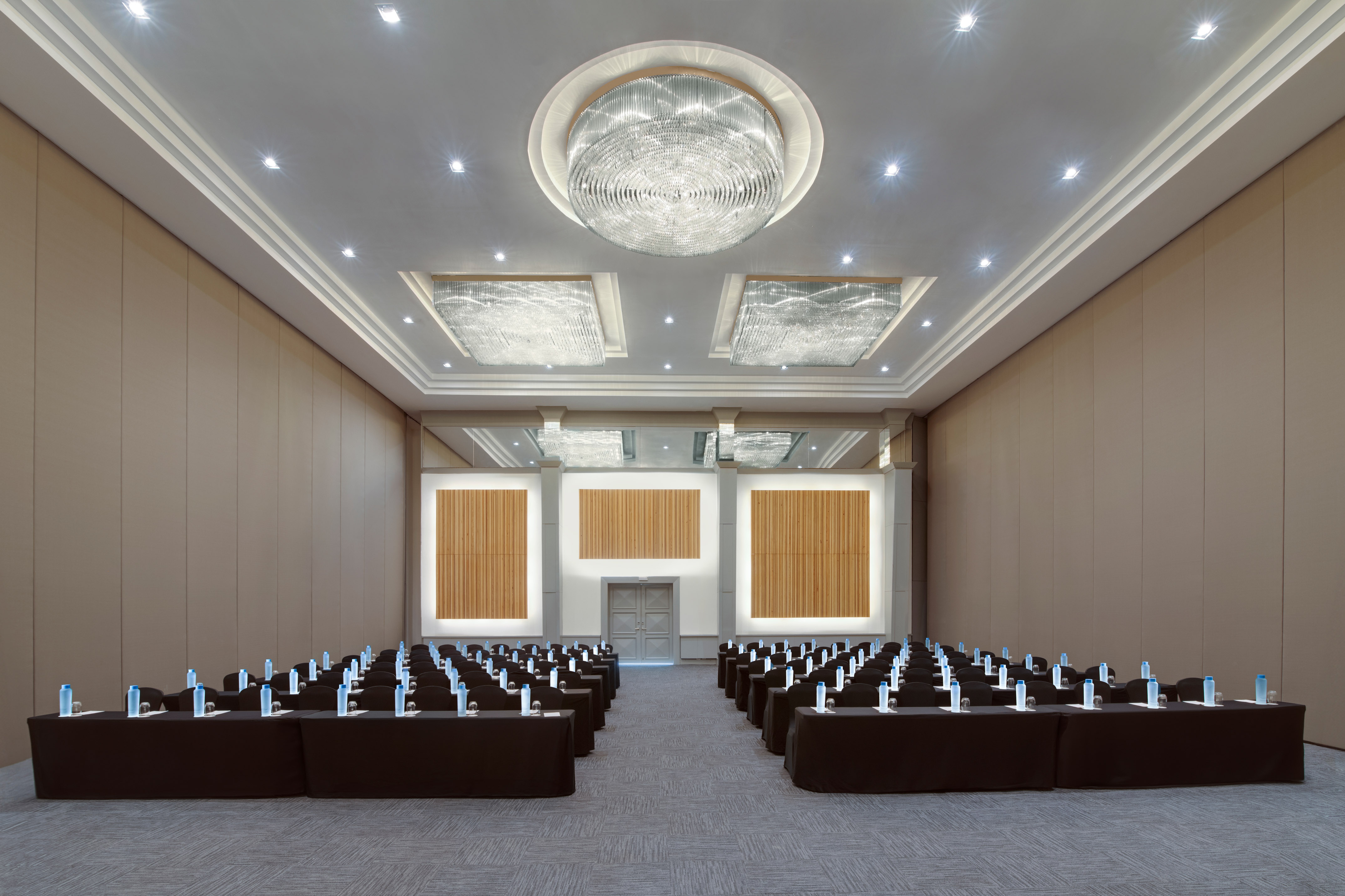 Modern conference room with tables, chairs, and elegant chandeliers for events.