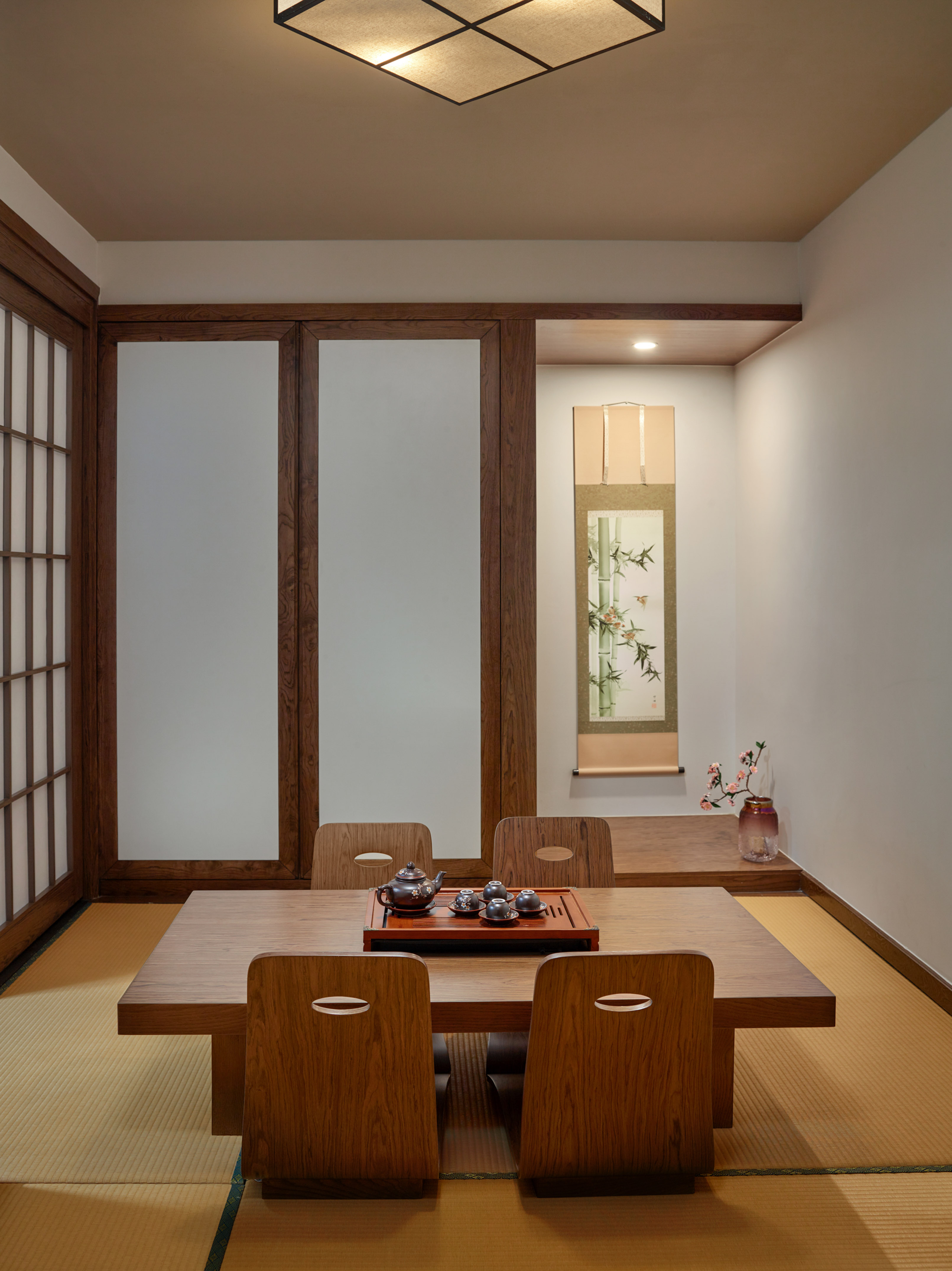 Japanese tatami room with low tea table, tea set, shoji screens, and scroll.