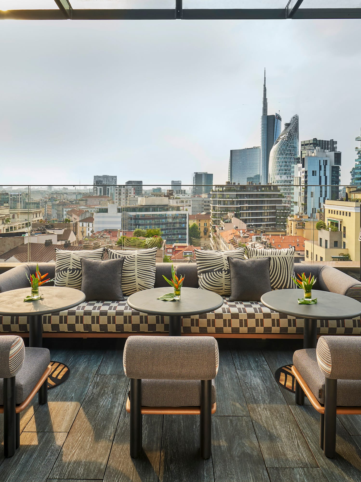 a rooftop patio with tables and chairs and a city view