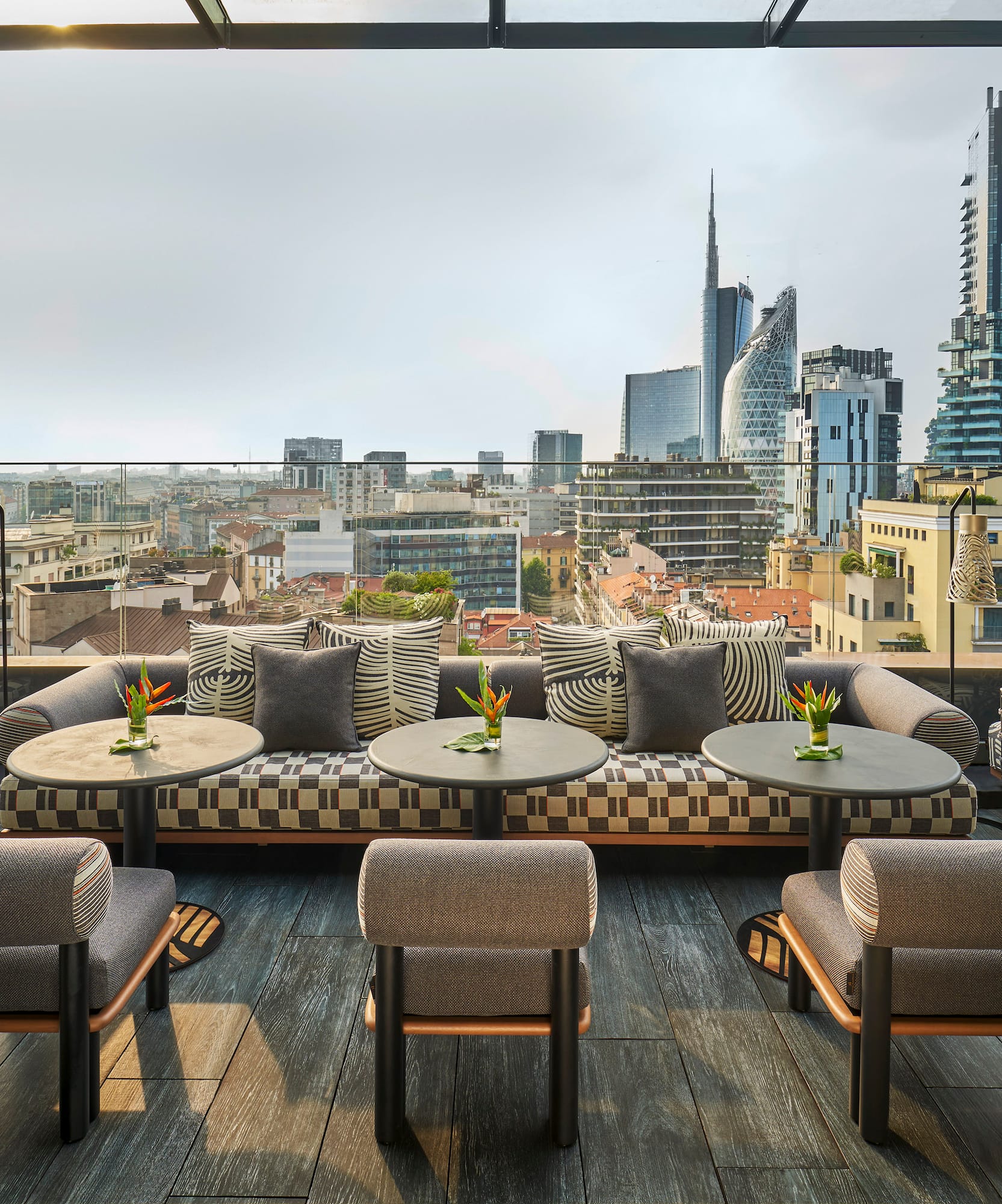 a rooftop patio with tables and chairs and a city view.