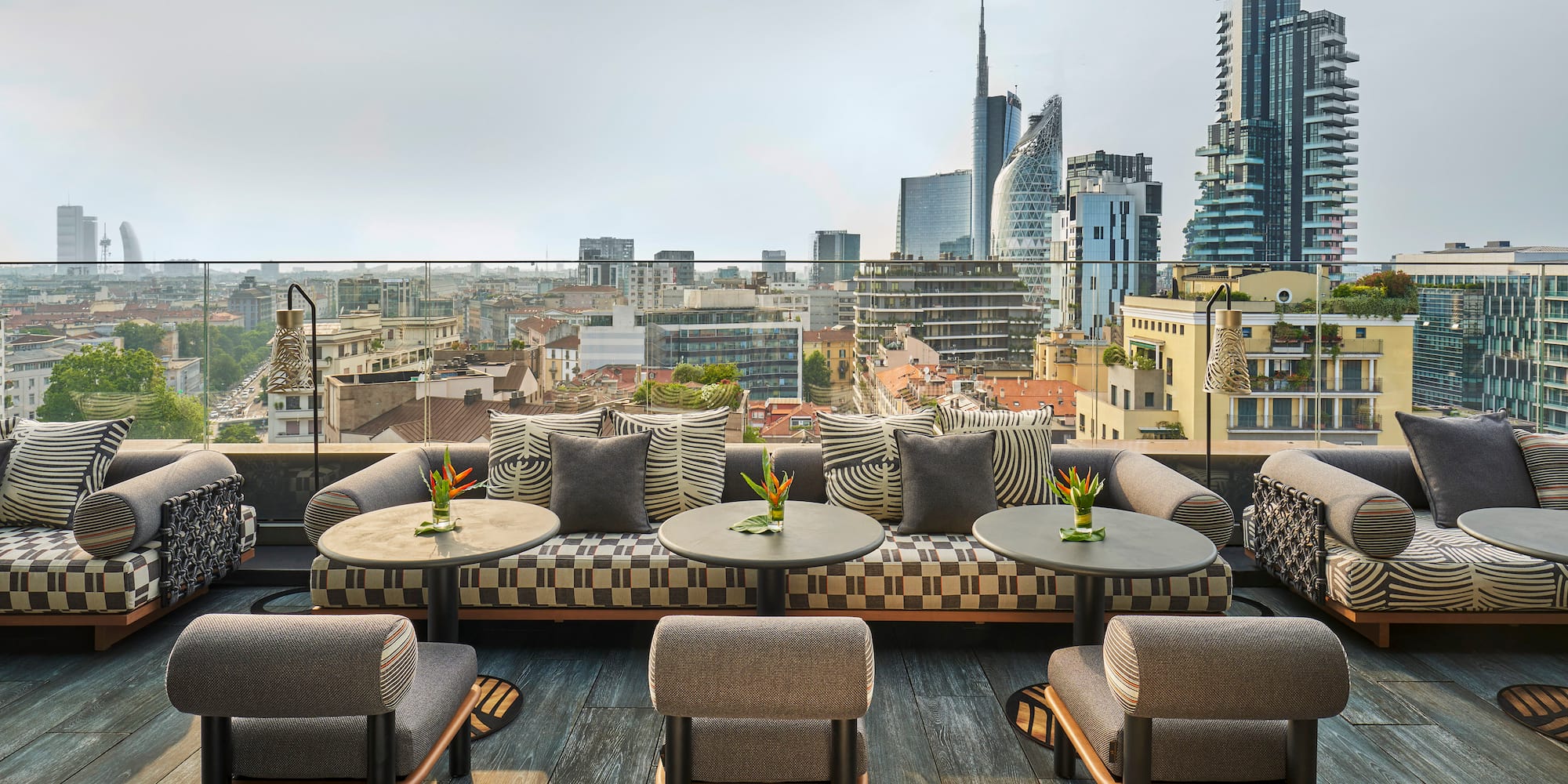 a rooftop patio with tables and chairs and a city view
