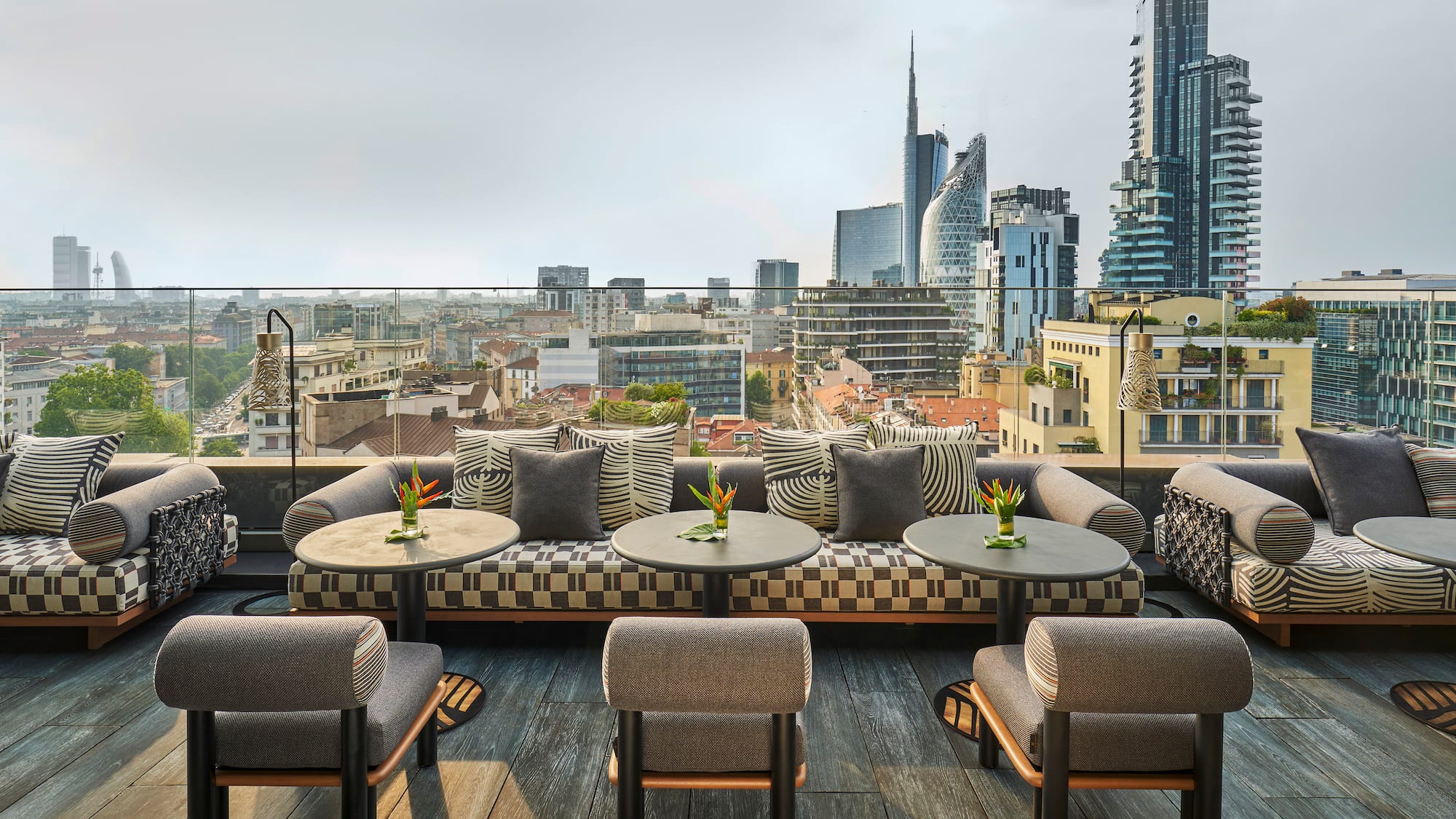 a rooftop patio with tables and chairs and a city view