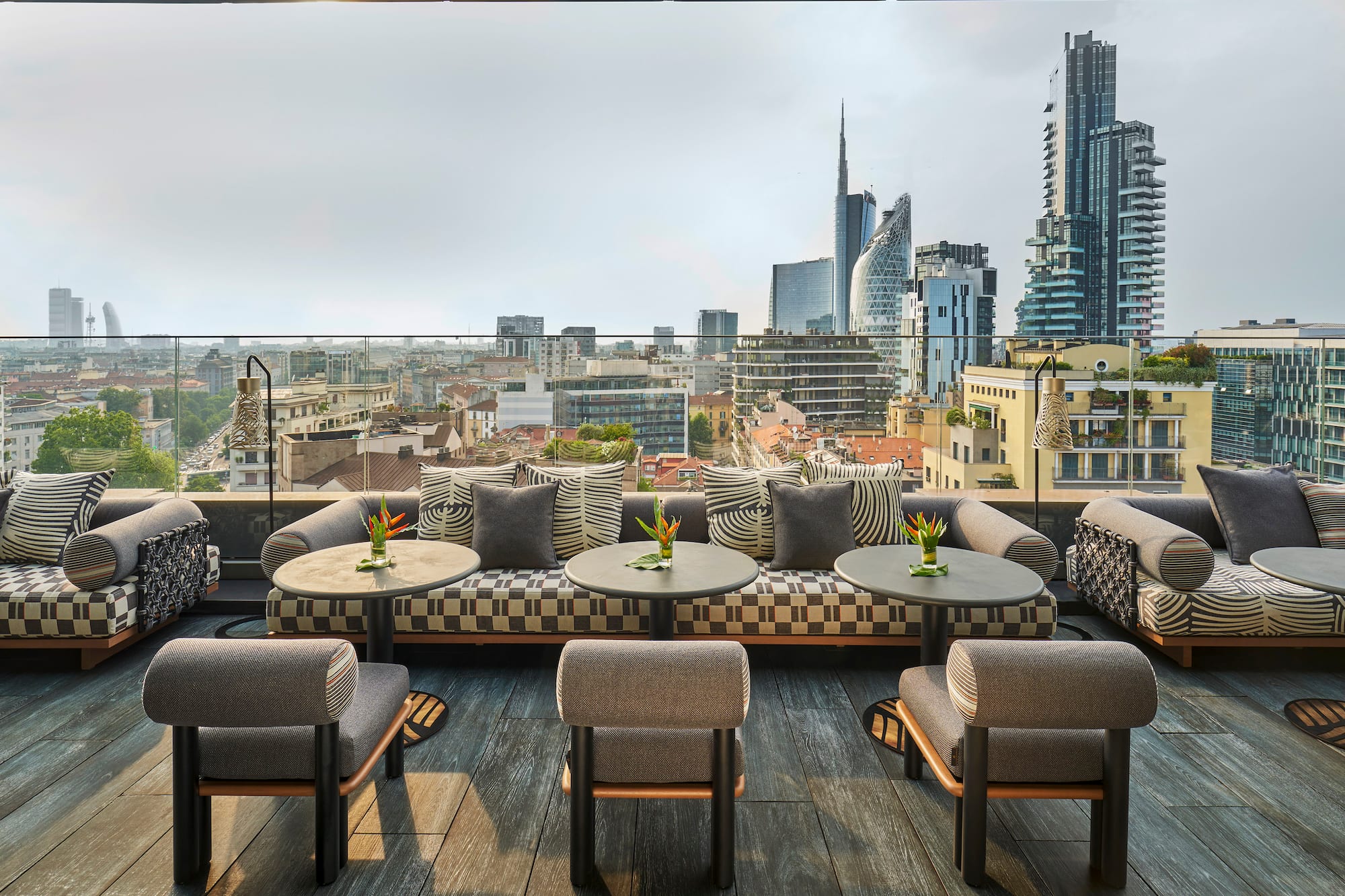 a rooftop patio with tables and chairs and a city view