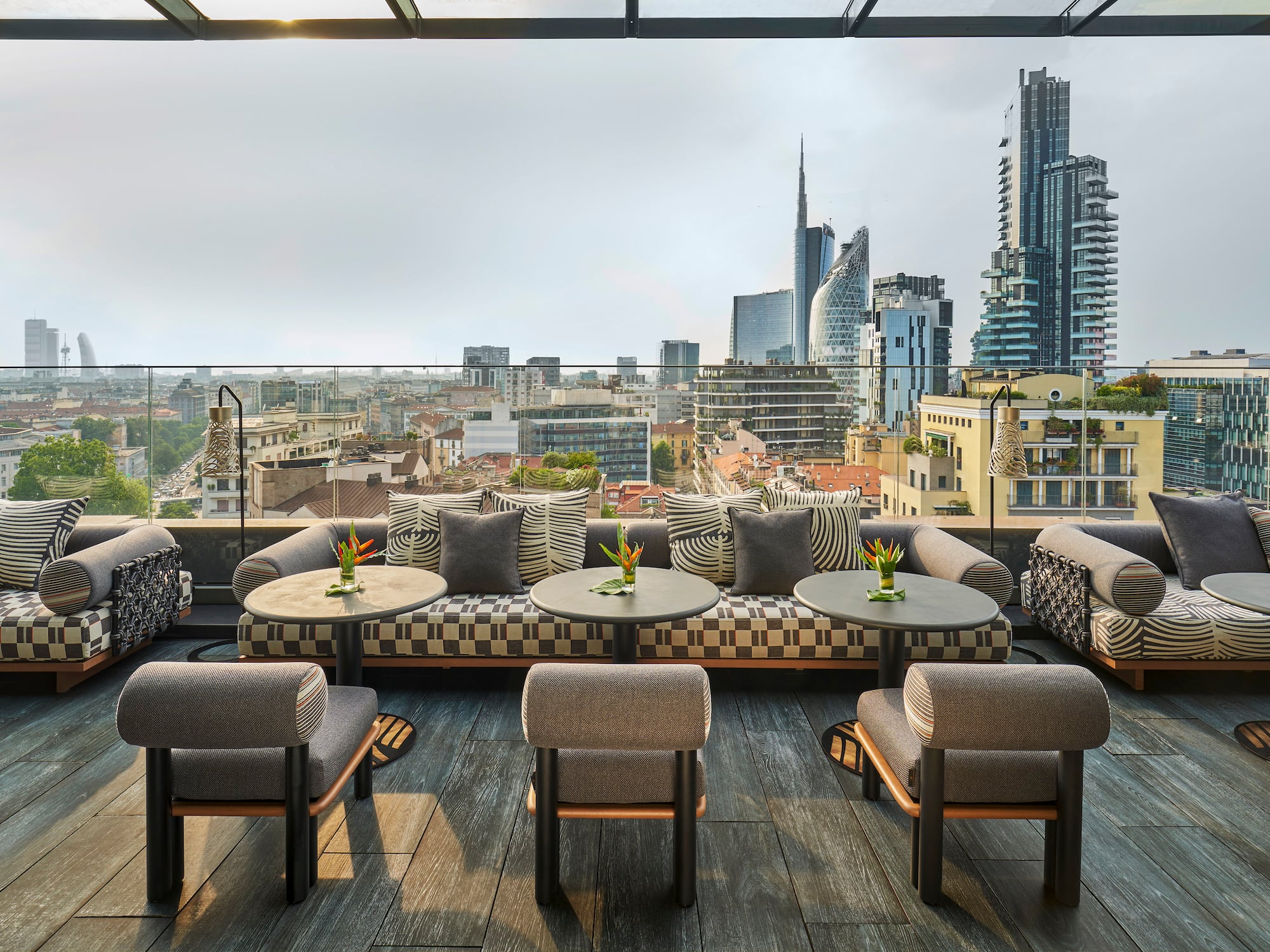 a rooftop patio with tables and chairs and a city view
