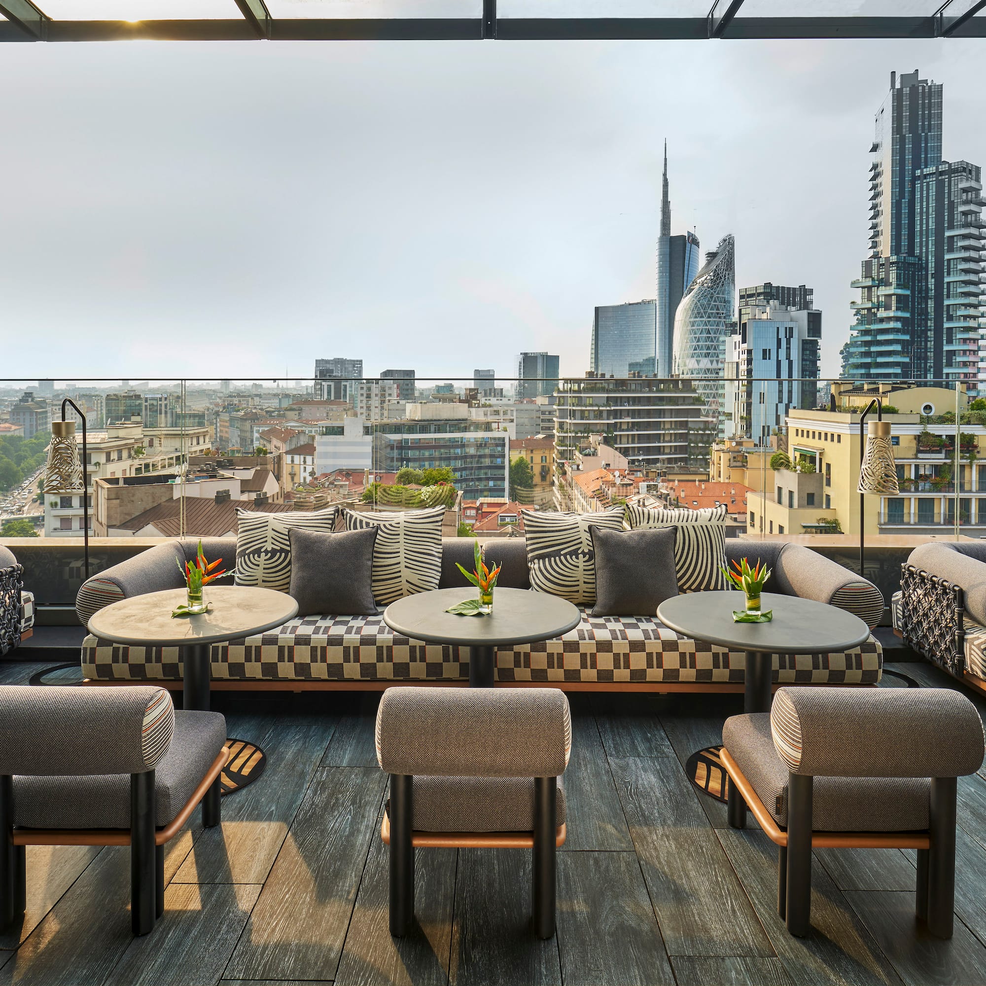 a rooftop patio with tables and chairs and a city view