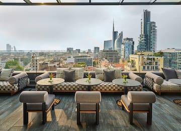 a rooftop patio with tables and chairs and a city view.