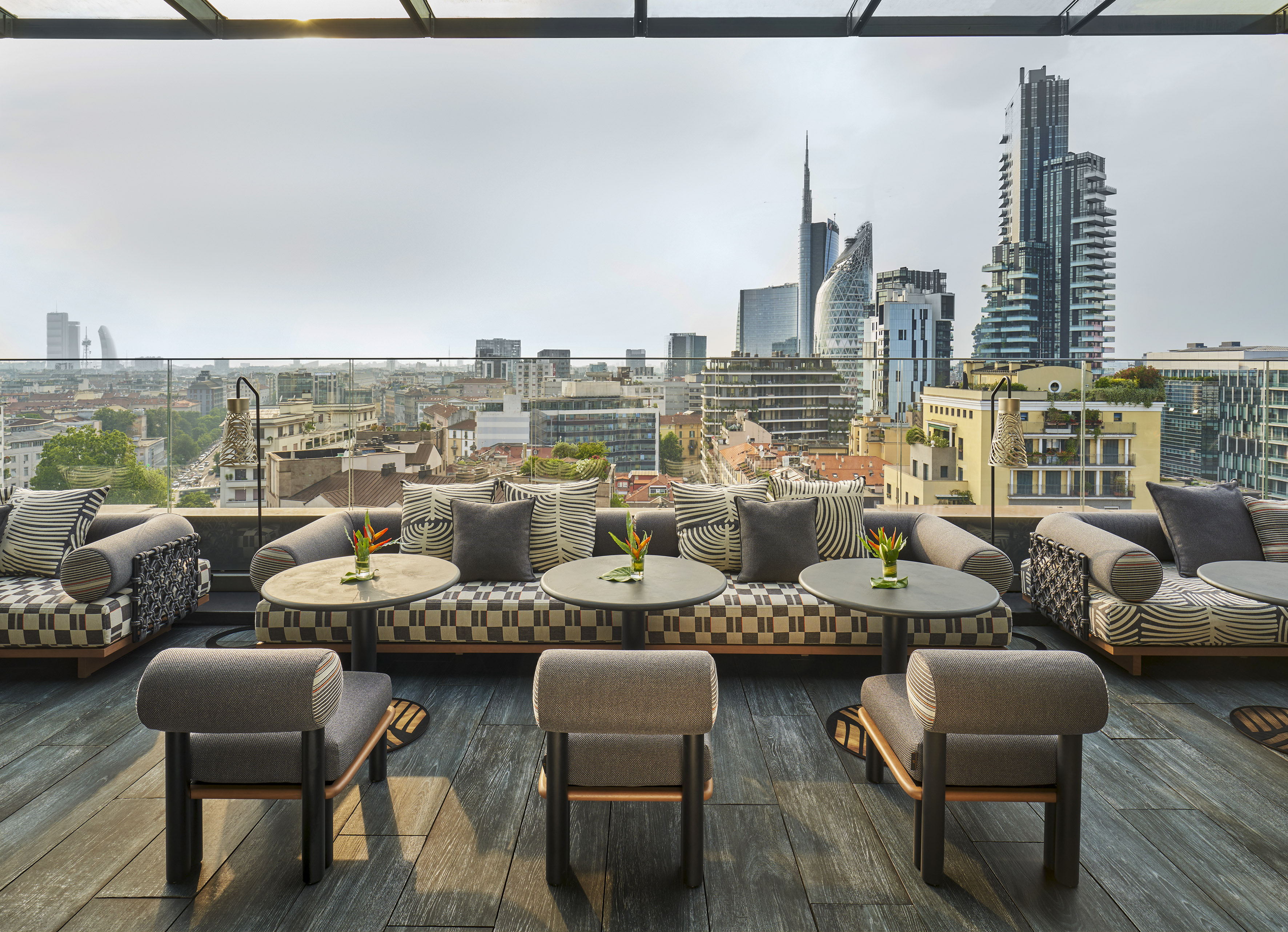 Milan rooftop lounge with modern seating and city skyline.