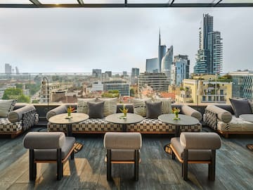 a rooftop patio with tables and chairs and a city view
