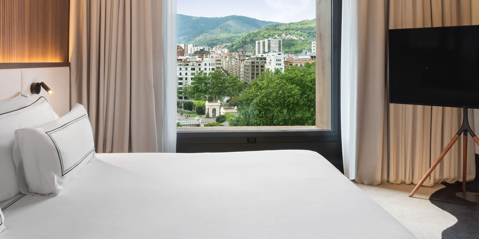 a bed with a television in front of a window