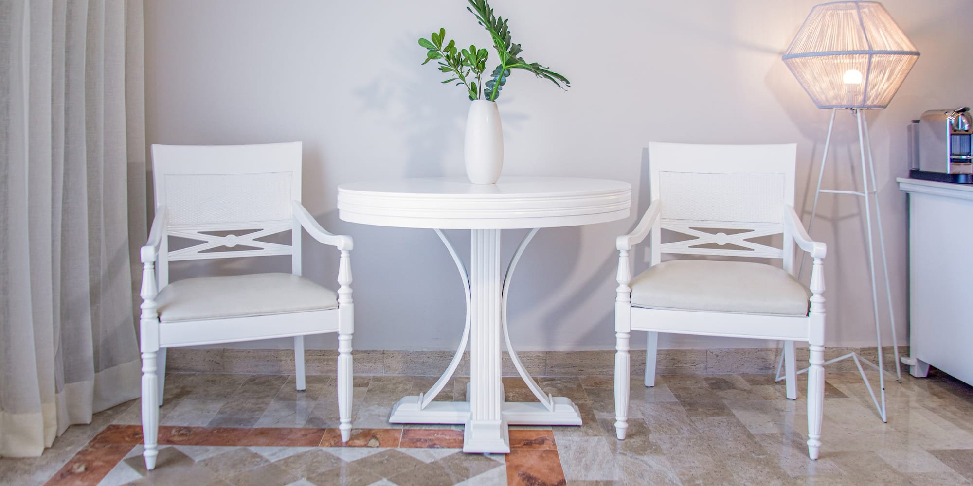 Bright modern room with white chairs, round table, and green plant.