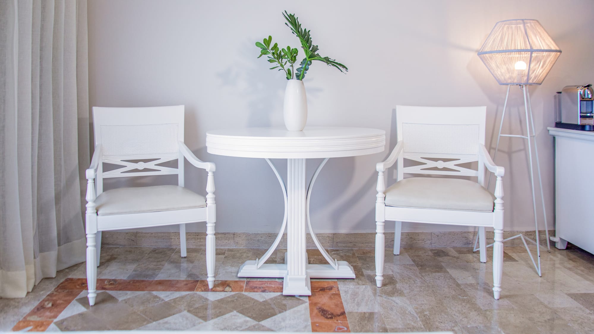 Bright modern room with white chairs, round table, and green plant.