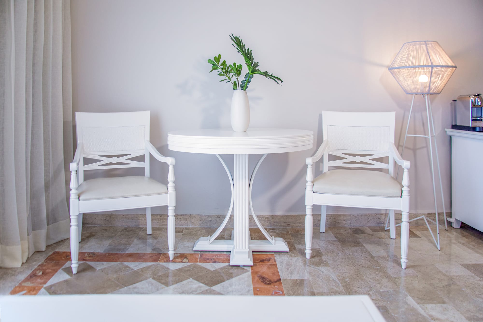 White armchairs, round table with vase, modern floor lamp, contemporary interior.