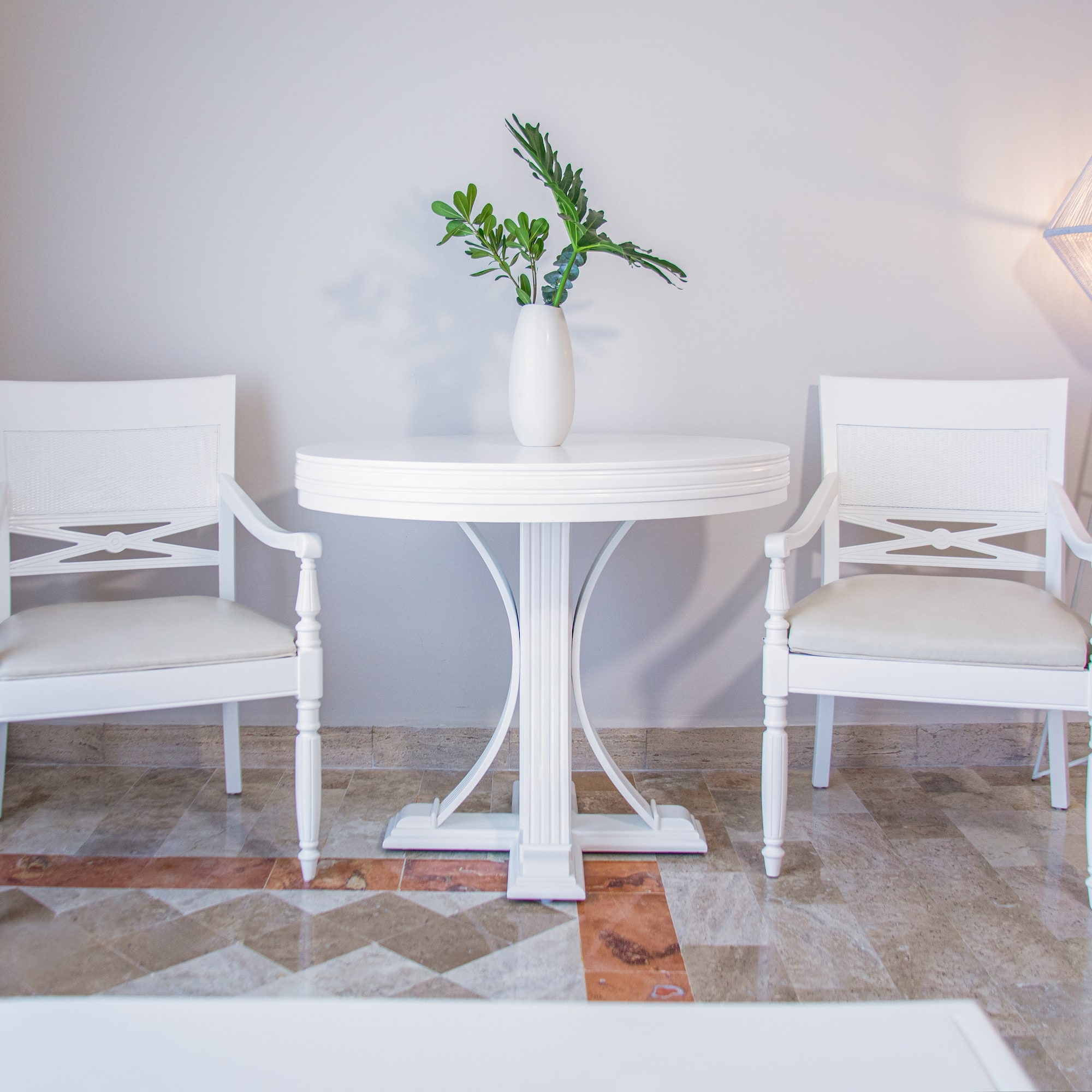 Bright modern room with white chairs, round table, and green plant.