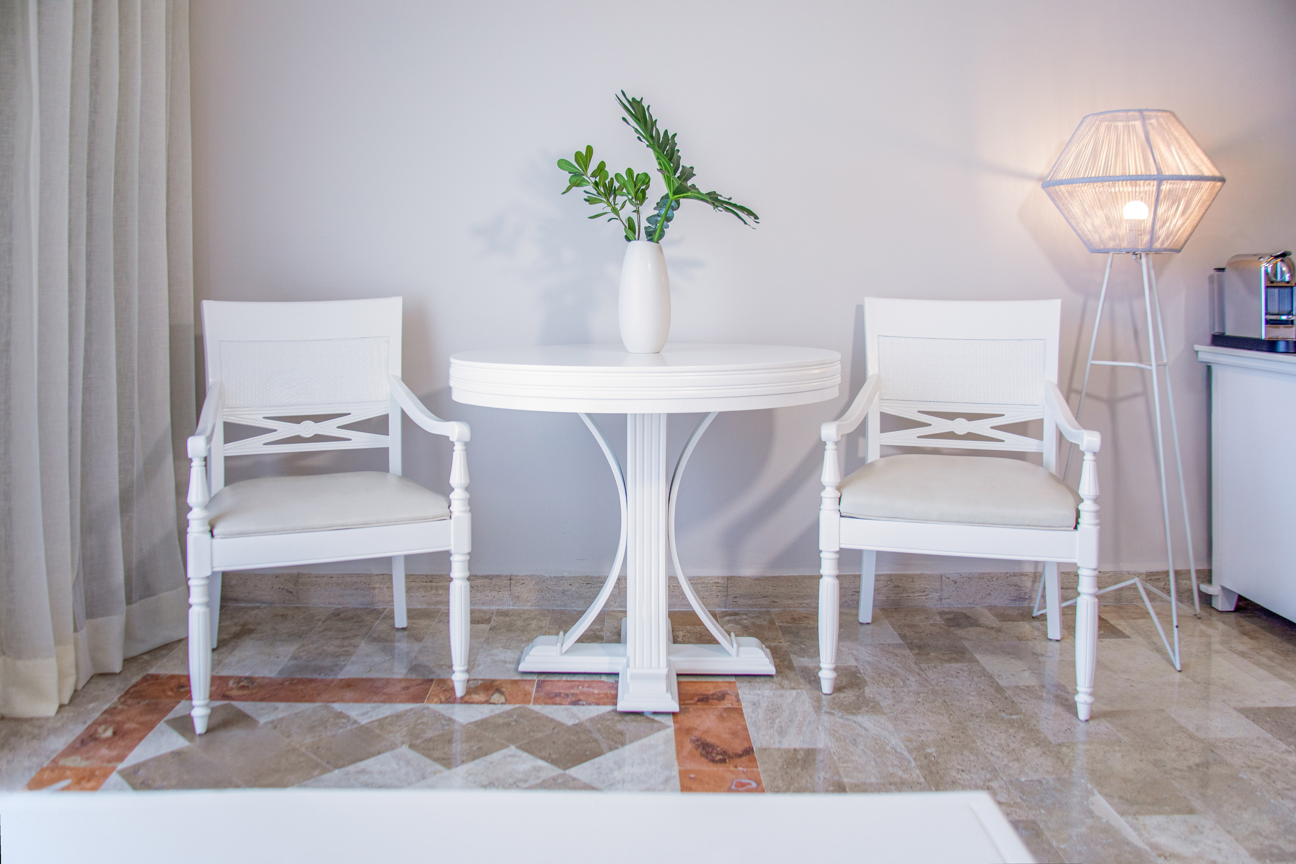 Bright modern room with white chairs, round table, and green plant.