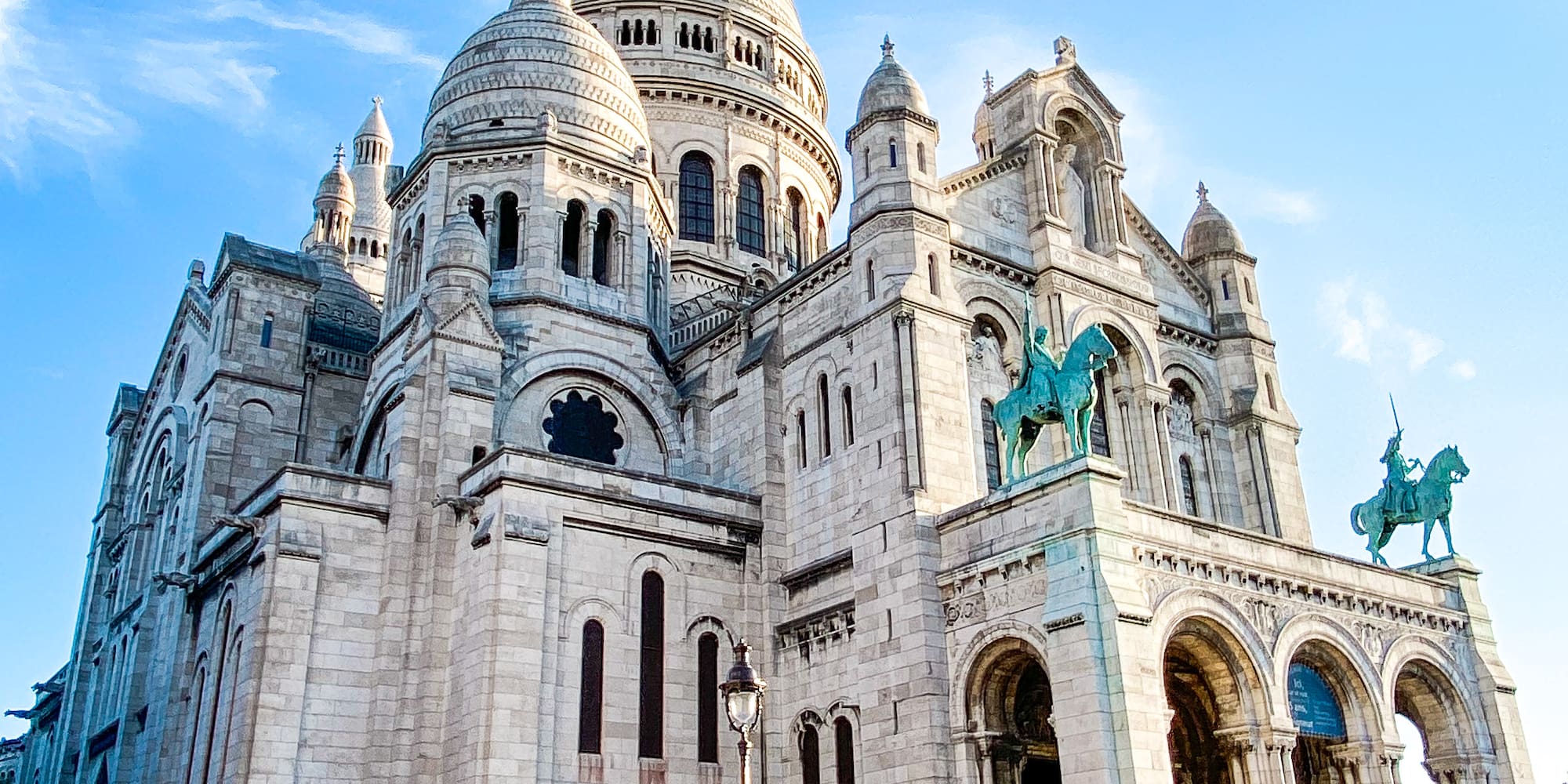 a large white building with a domed roof and a blue sky with Sacré-Cœur, Paris in the background