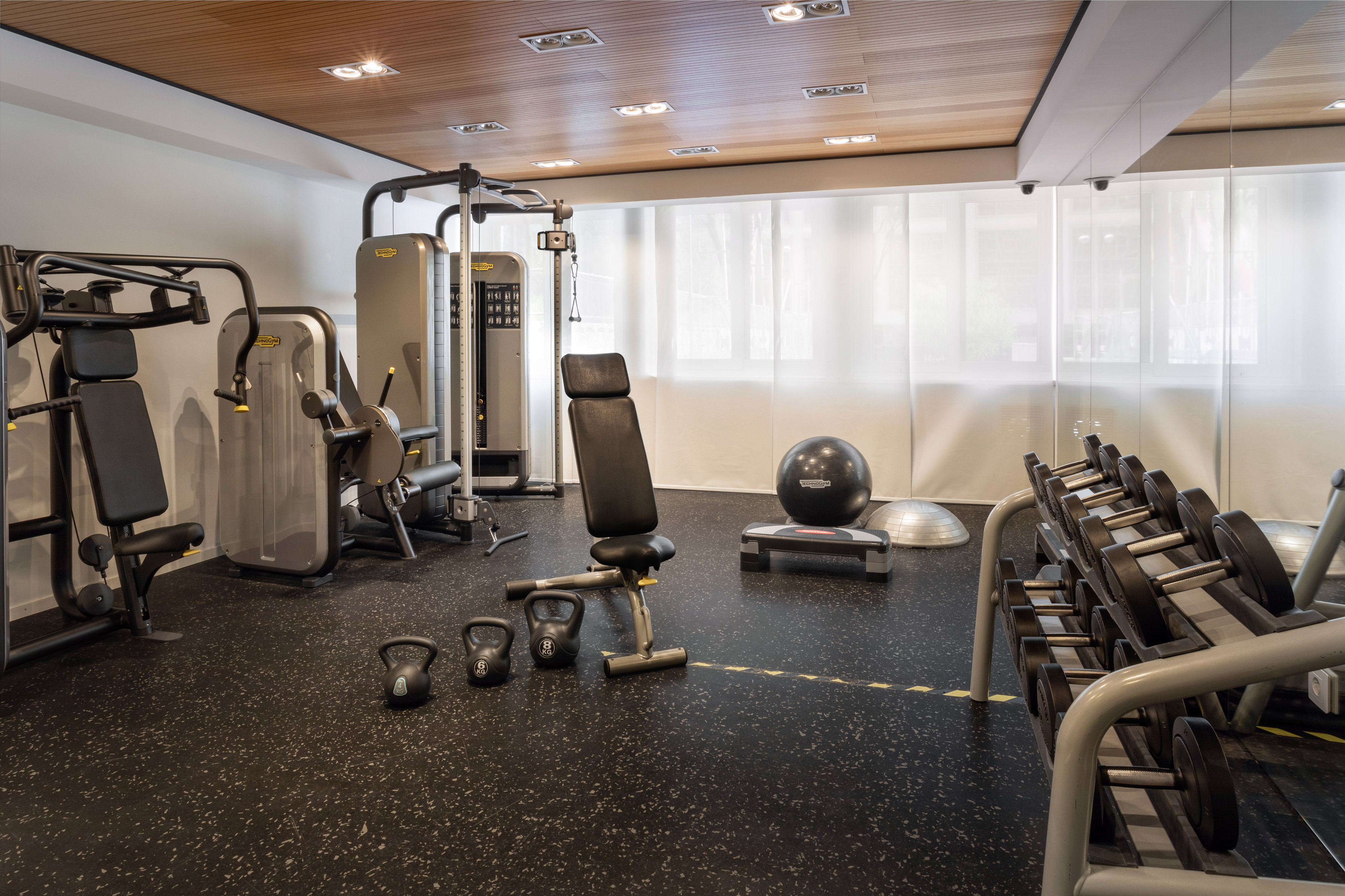 Modern gym with strength machines, dumbbells, kettlebells, and fitness equipment.