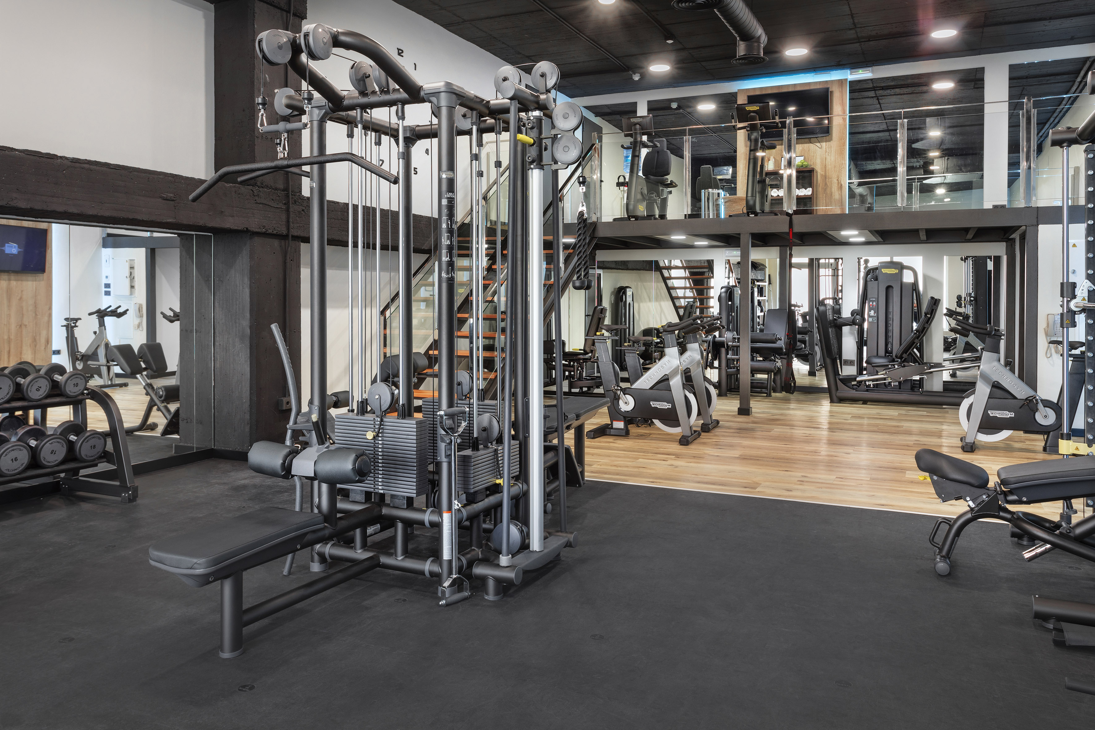 Multi-level modern gym with diverse fitness equipment and workout machines.
