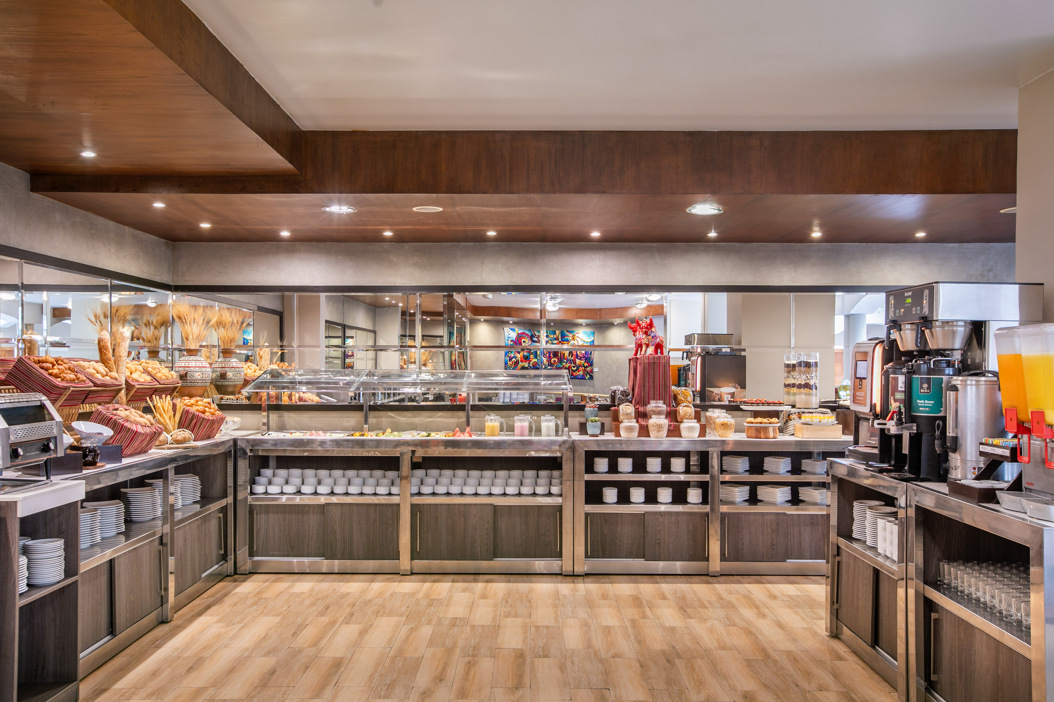 Modern hotel breakfast buffet spread with warm lighting, baked goods, and drinks. - Hotel Cusco La Paccha Affiliated by Meliá, Cusco