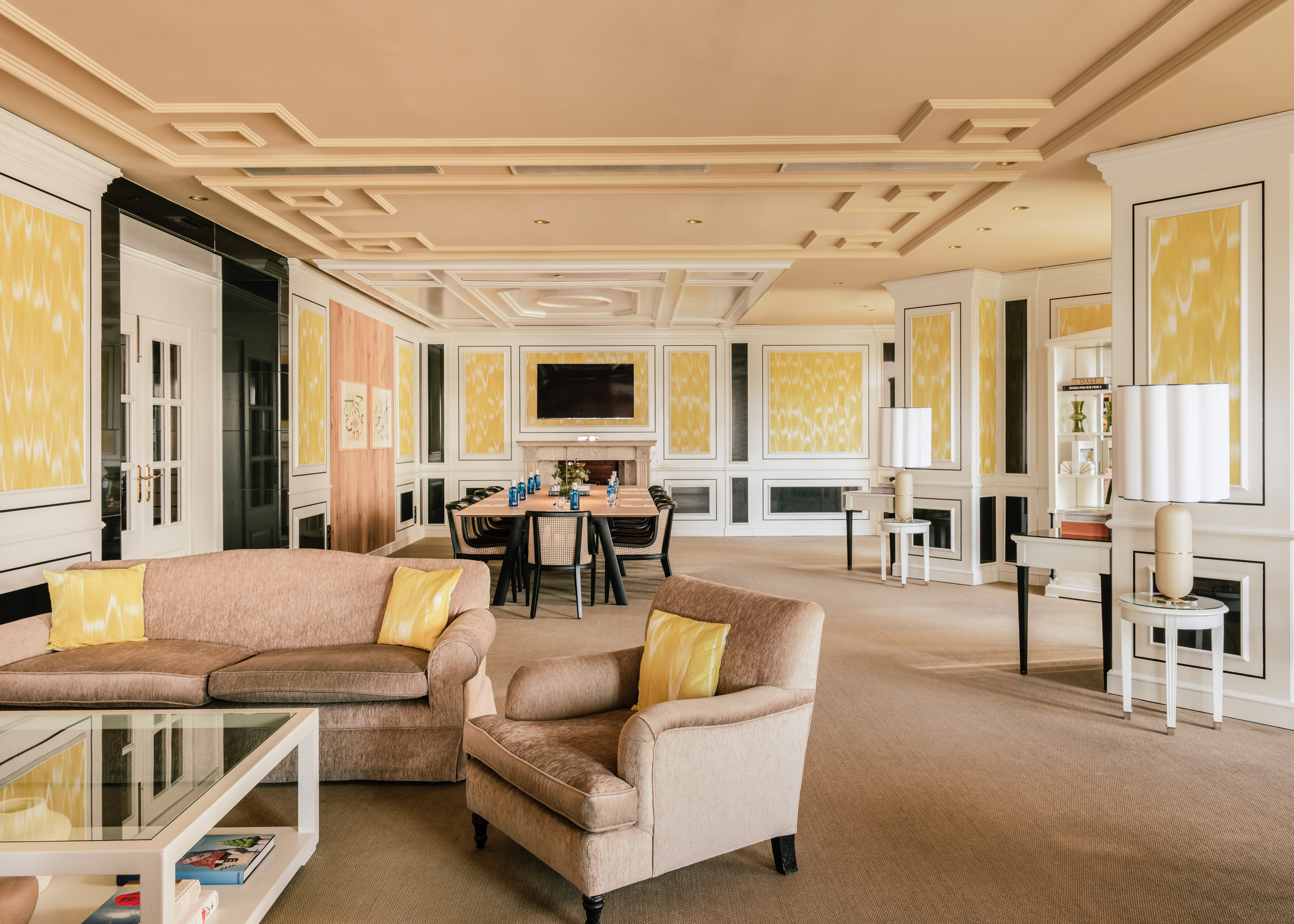 Elegant lounge with beige seating, yellow wall decor, and formal dining table.
