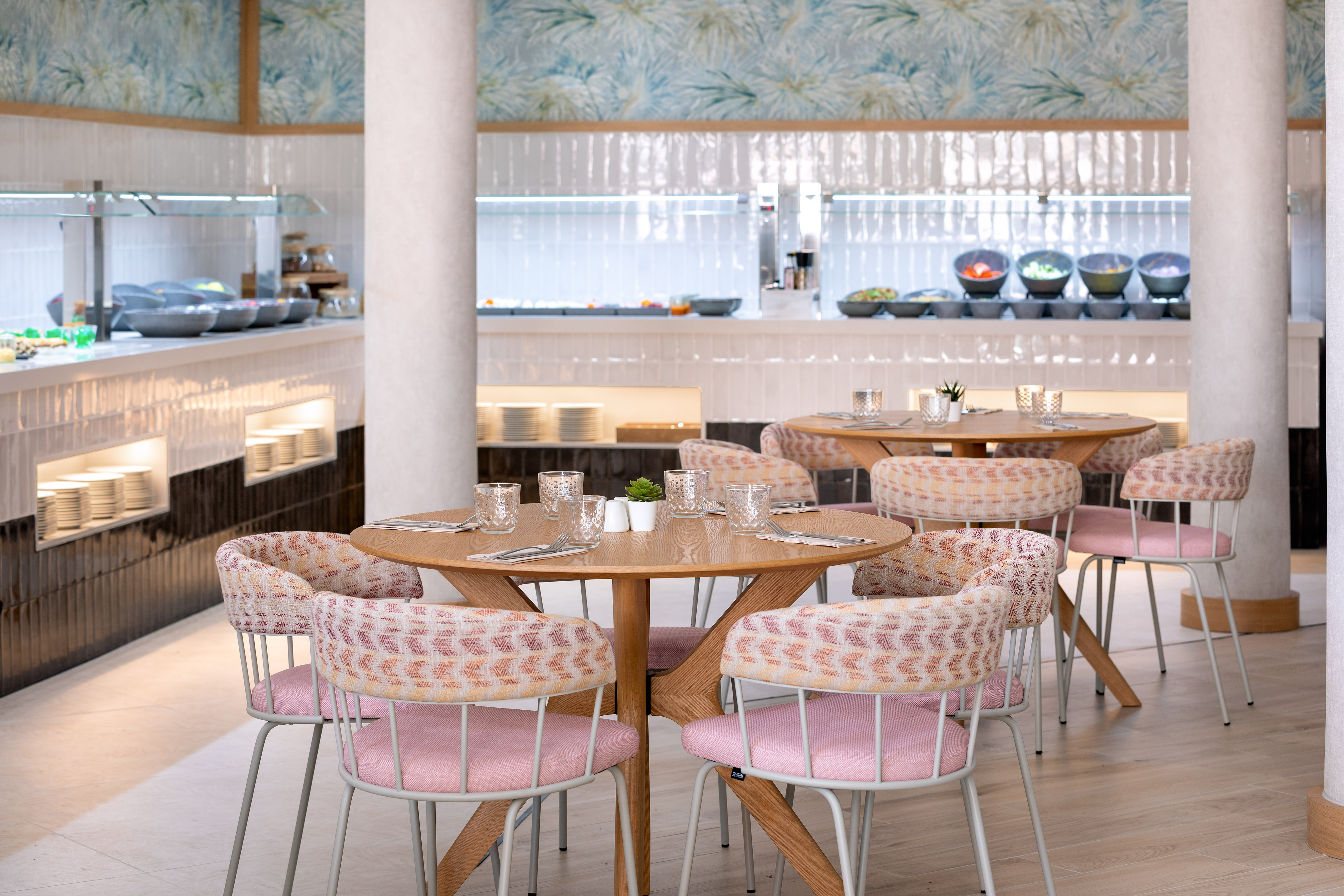 Modern restaurant interior featuring buffet, wooden tables, and pink chairs.