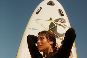 a woman in a wet suit holding a surfboard