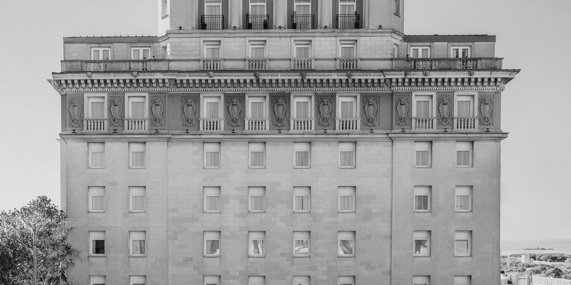 Ornate black and white historic hotel with classical columns and spire.