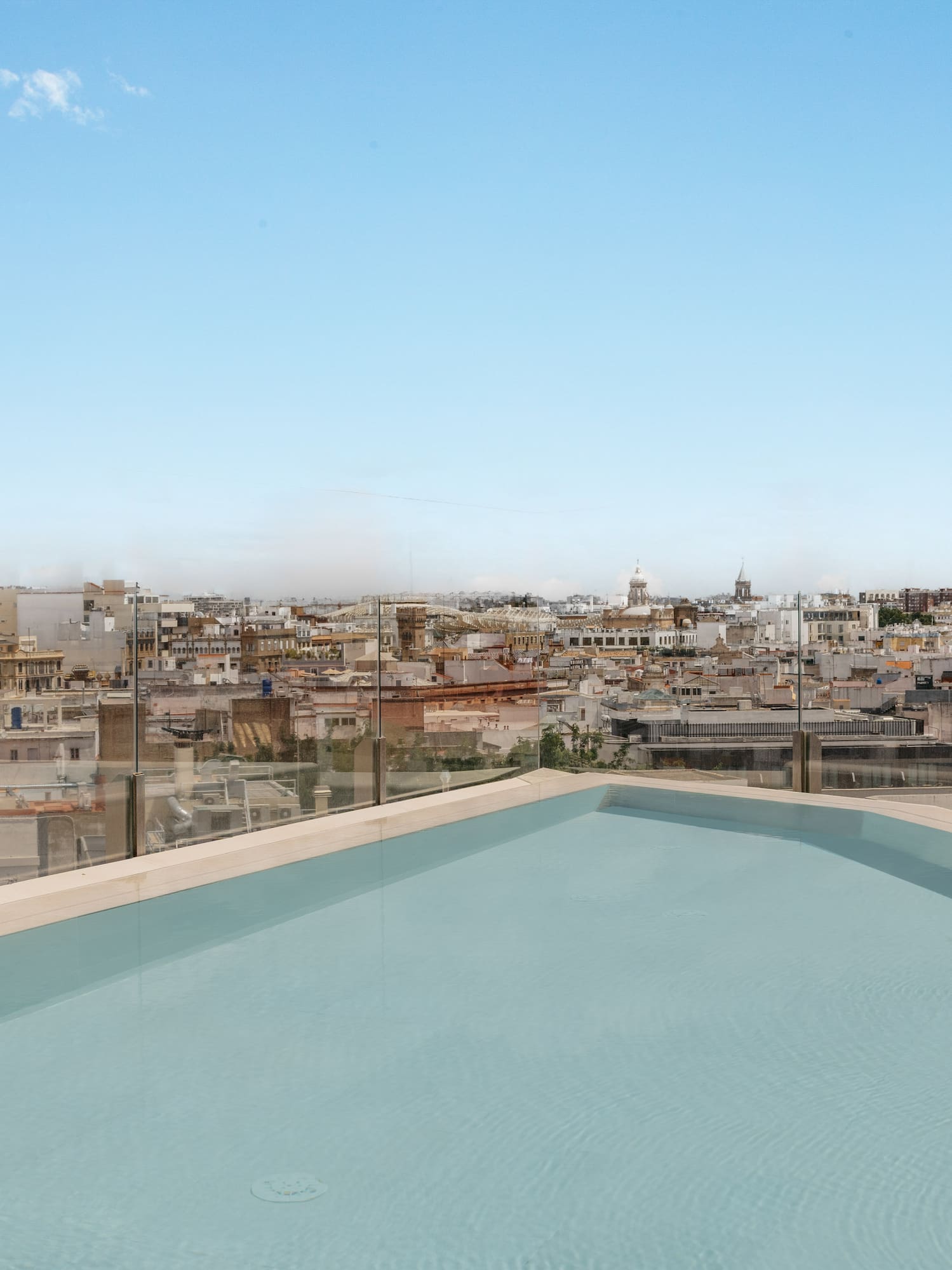 Luxury rooftop pool with city skyline view and blue sky.