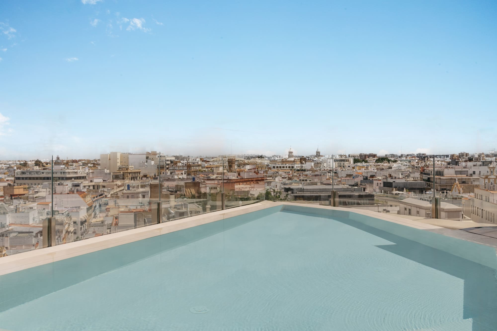 Piscina en azotea con vista panorámica de ciudad y cielo azul.