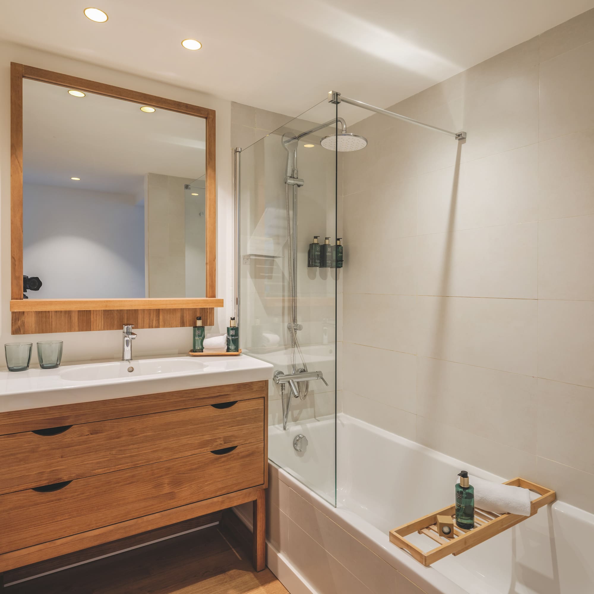 Contemporary bathroom with wooden vanity, mirror, bathtub, and glass shower.