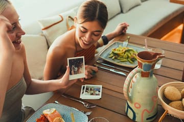 a woman sitting at a table with food and pictures