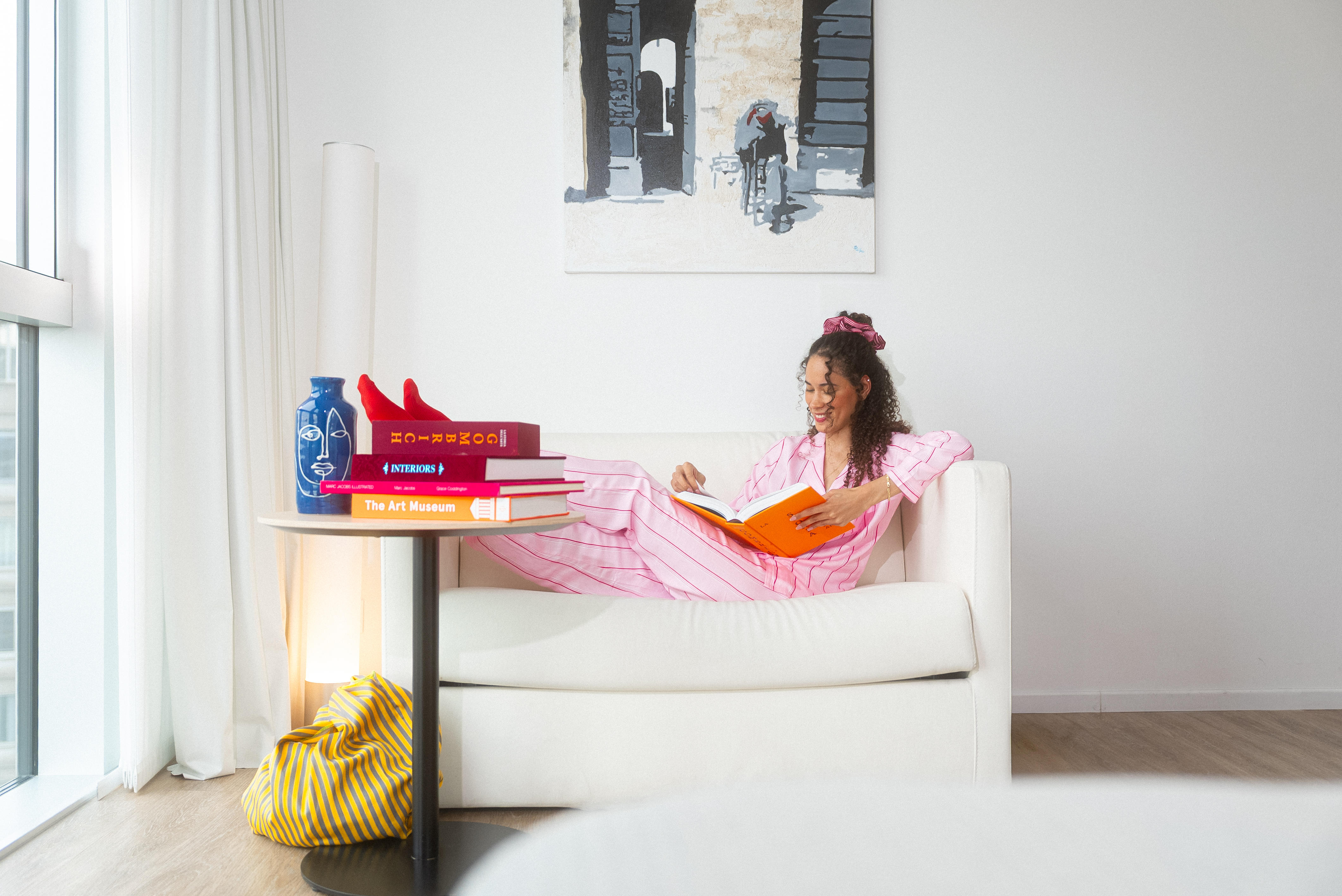 a woman in pajamas reading a book on a couch