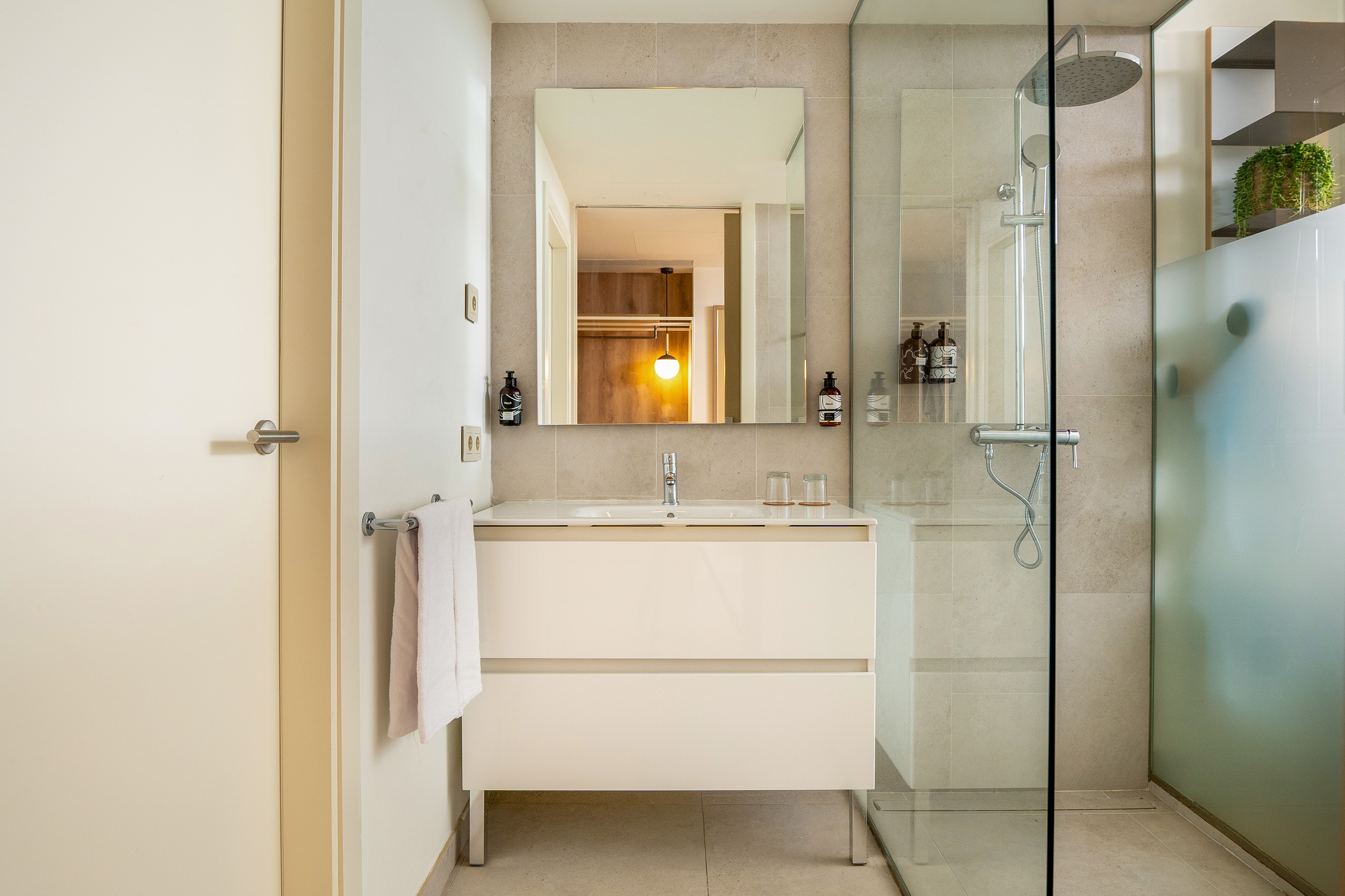 Modern bathroom with white vanity, mirror, and glass walk-in shower.