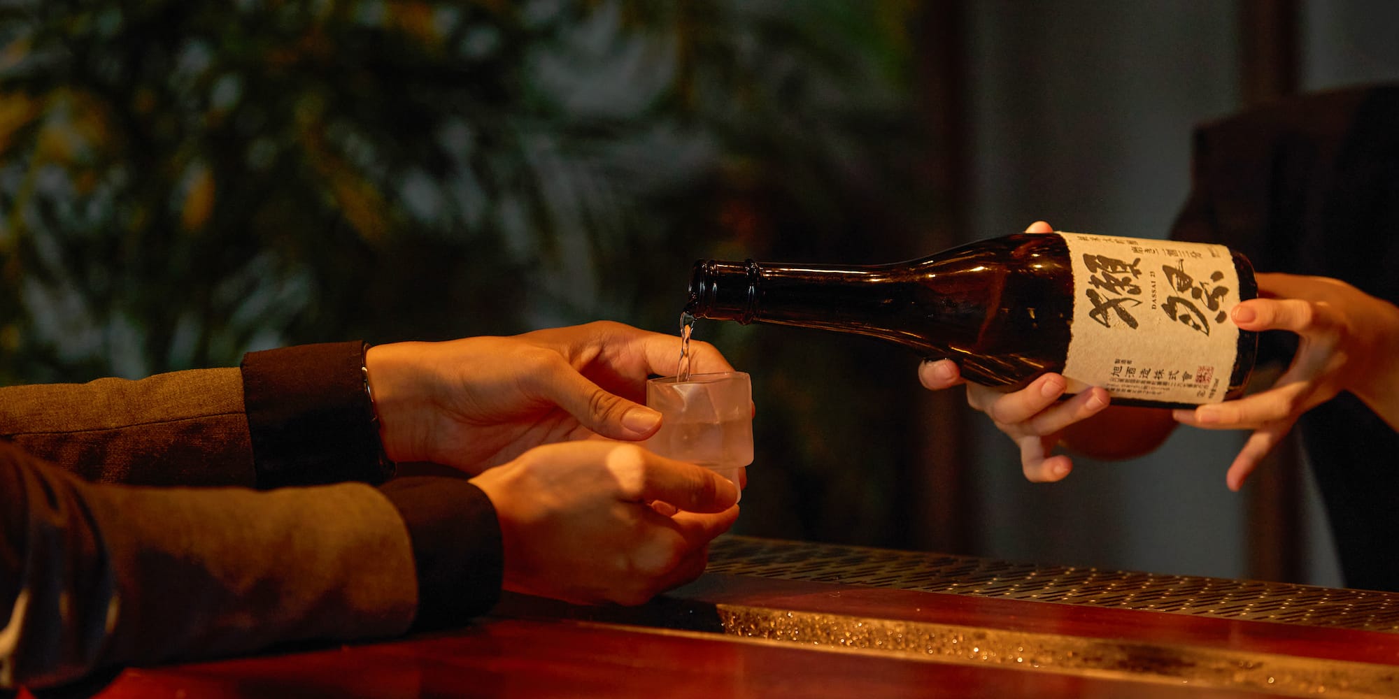 a person pouring a drink into a glass