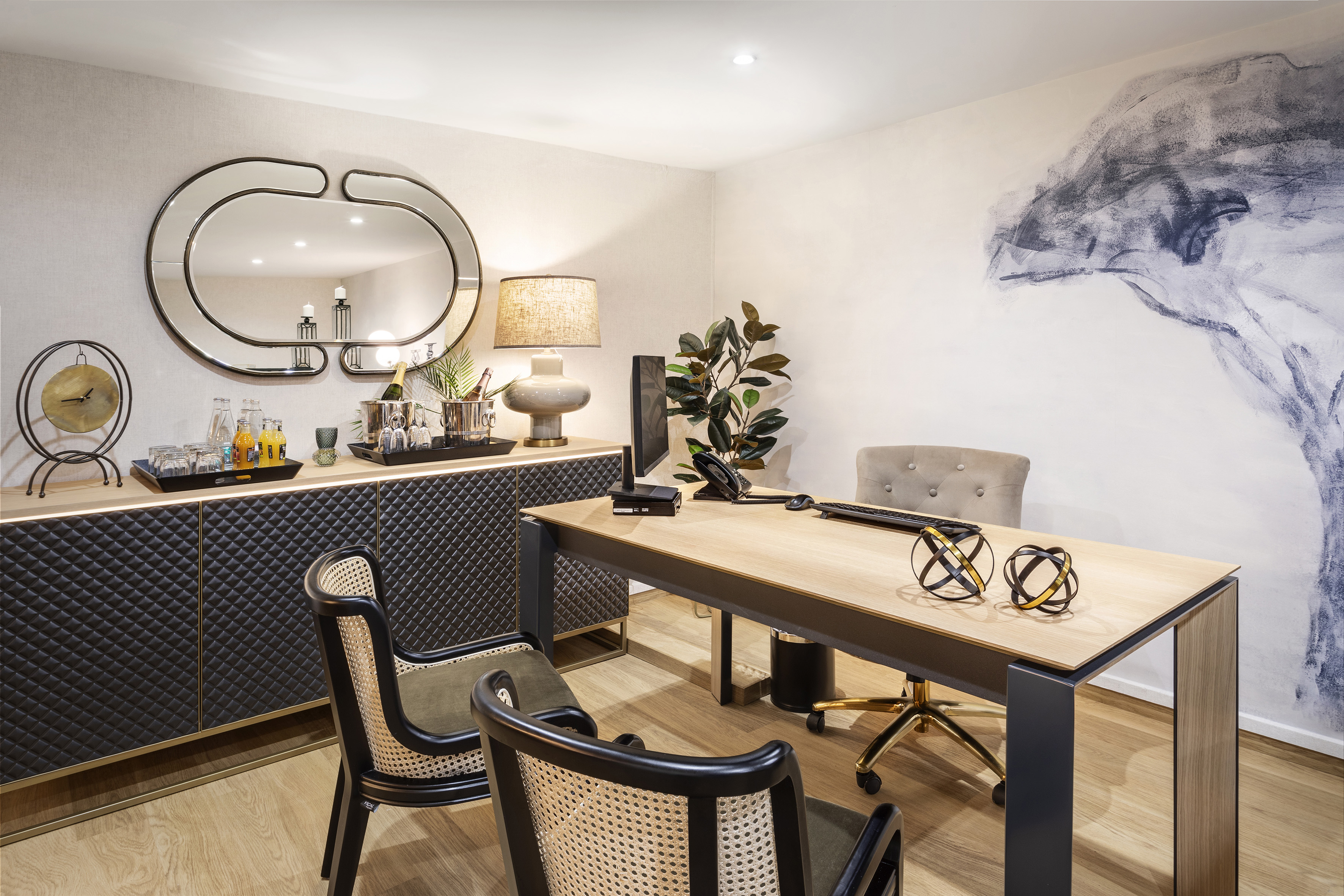 Modern executive office with wooden desk, stylish chairs, and bar credenza.
