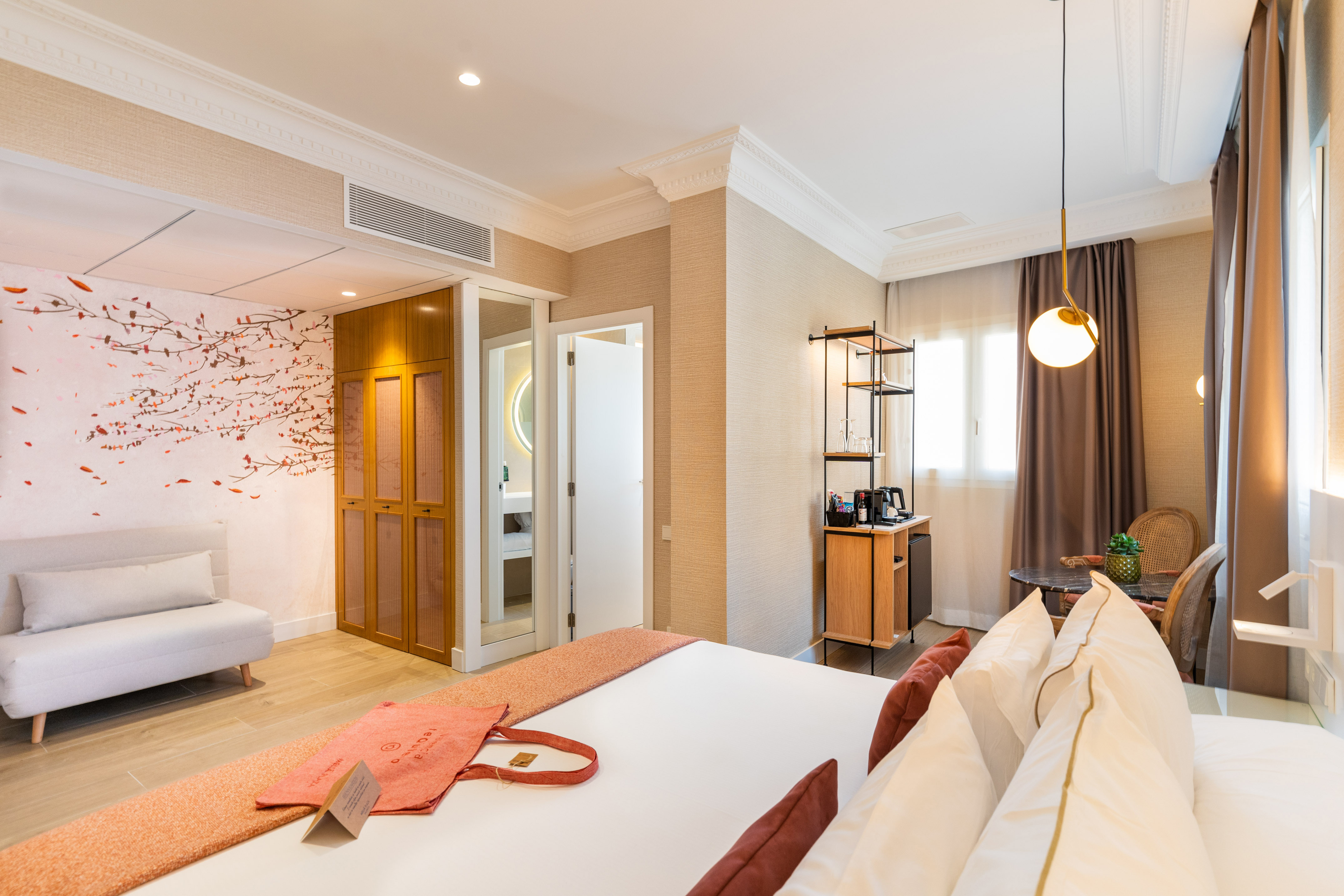 Contemporary hotel room with comfortable bed, accent wall, and minibar.