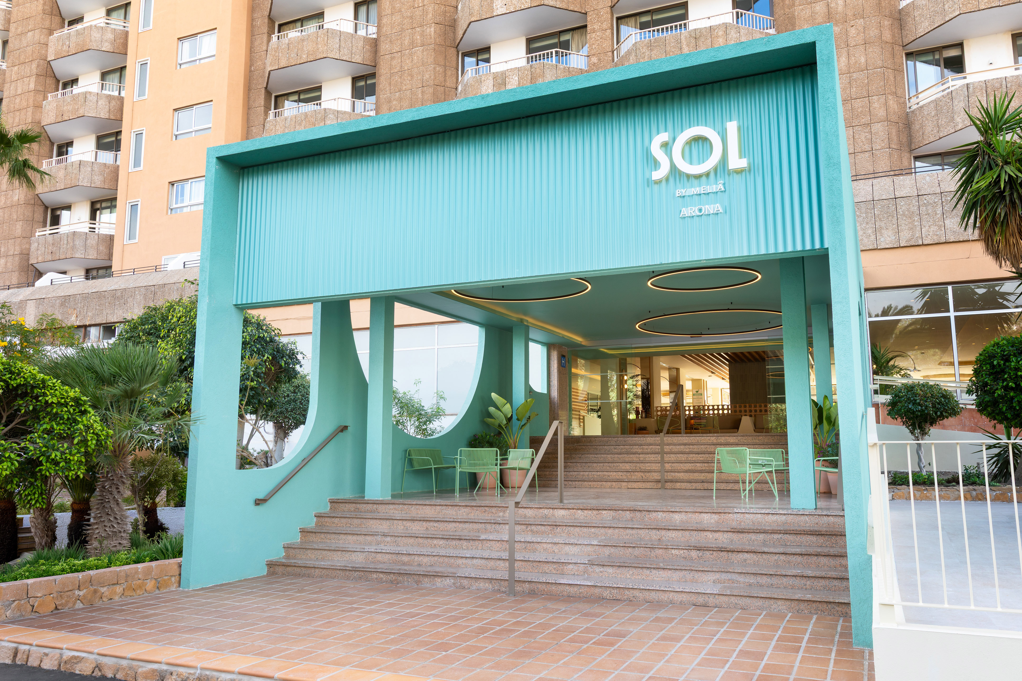 Modern Sol by Meliá hotel entrance, teal facade, steps, and tropical plants.