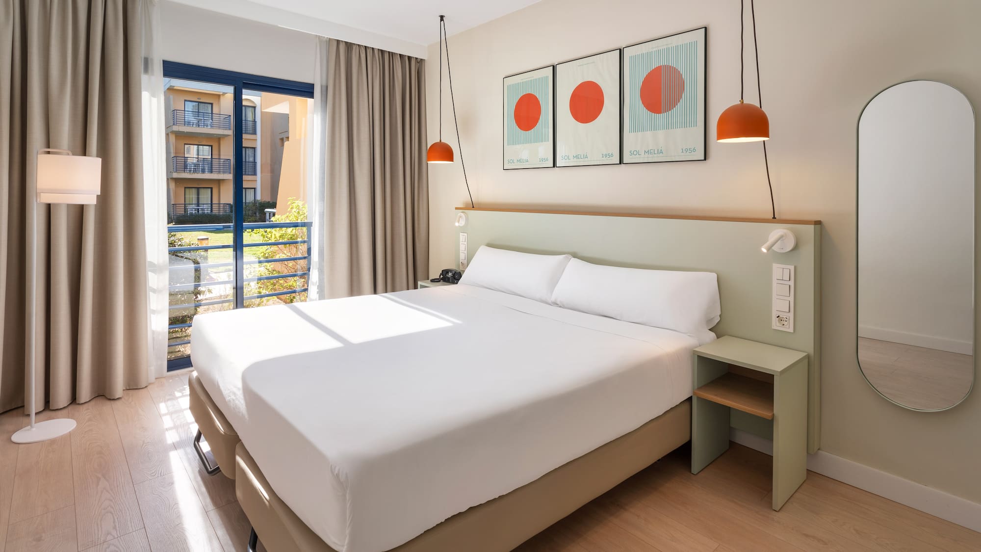 a bed with white sheets and orange lamps