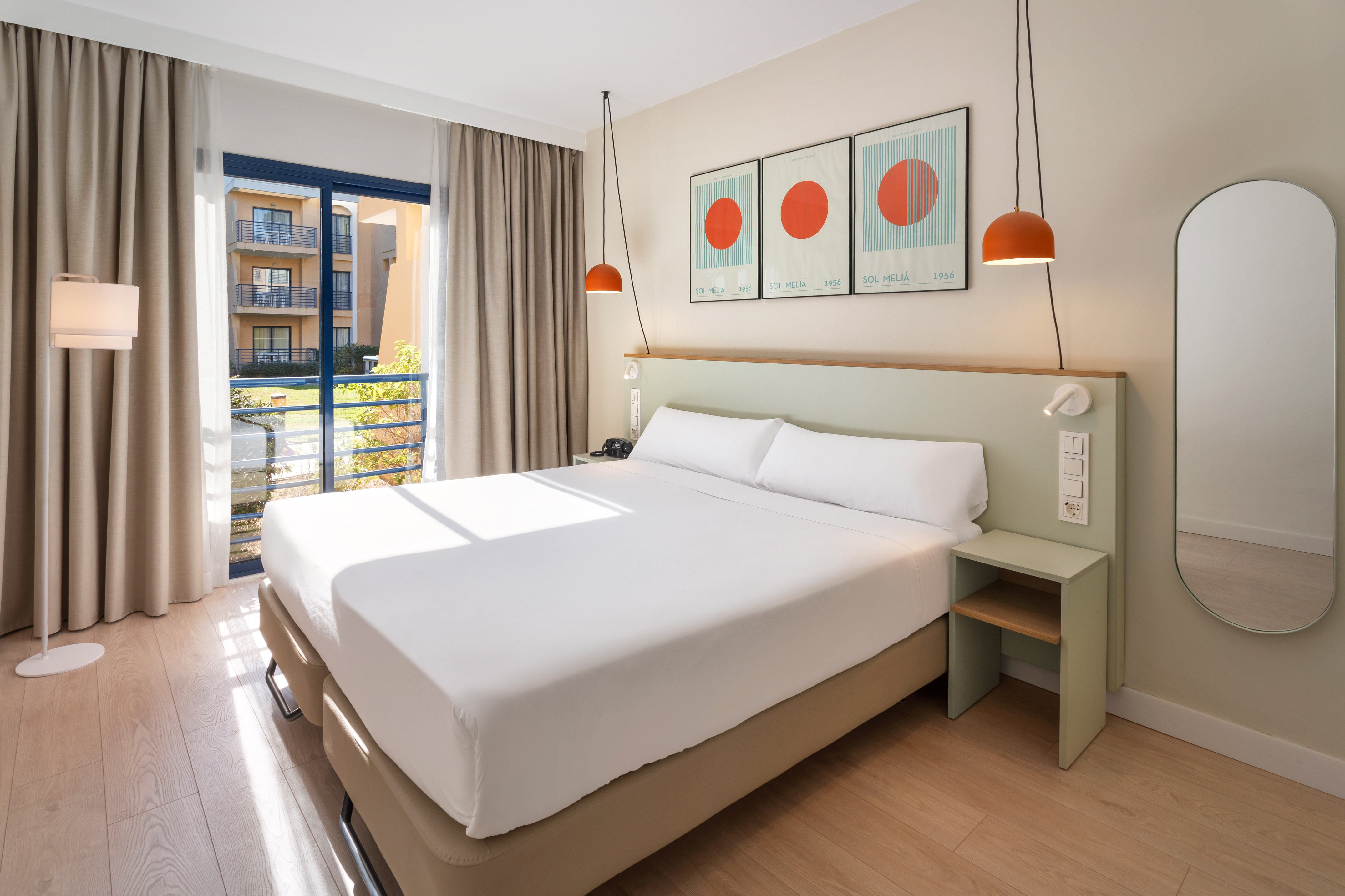 a bed with white sheets and orange lamps