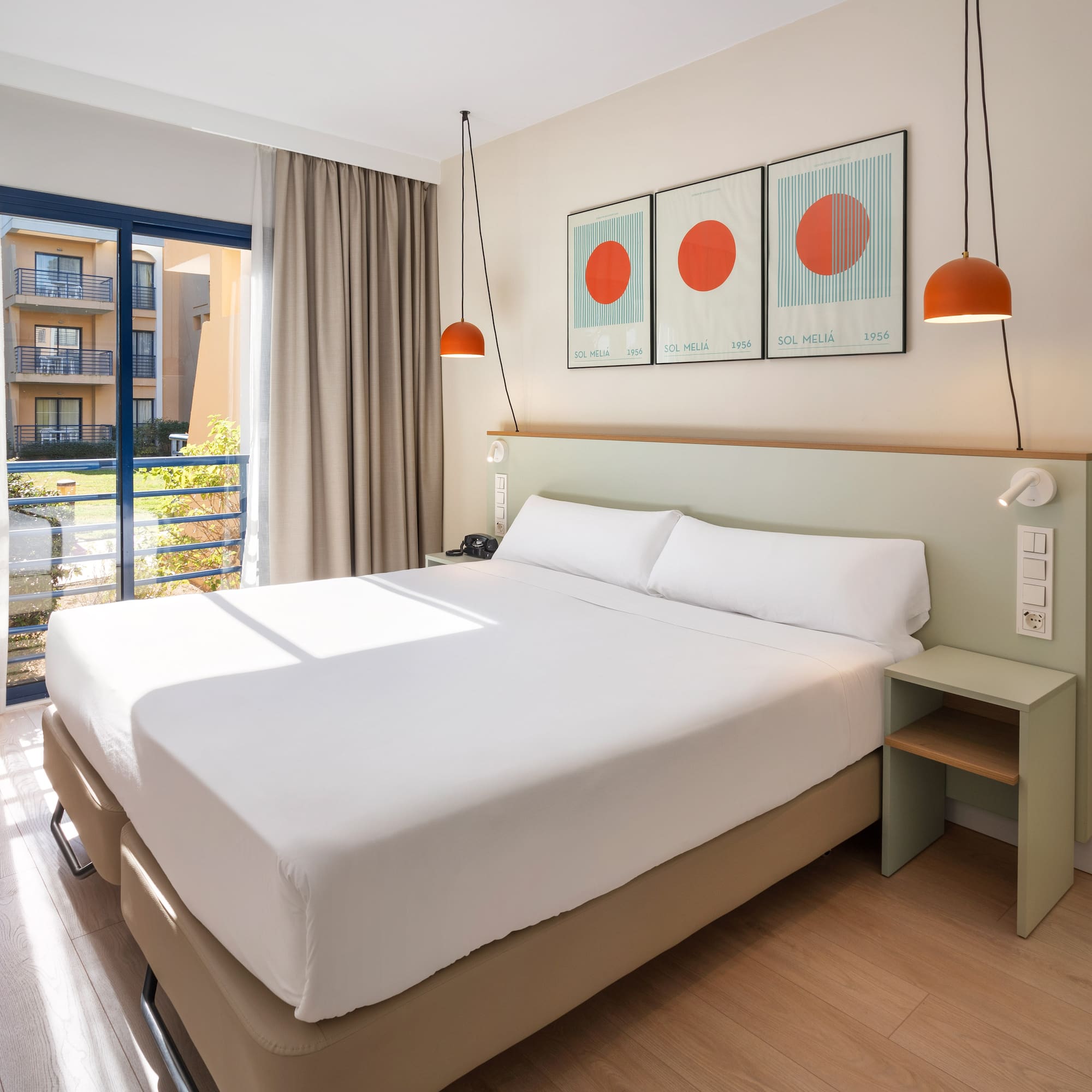 a bed with white sheets and orange lamps