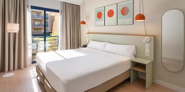 a bed with white sheets and orange lamps