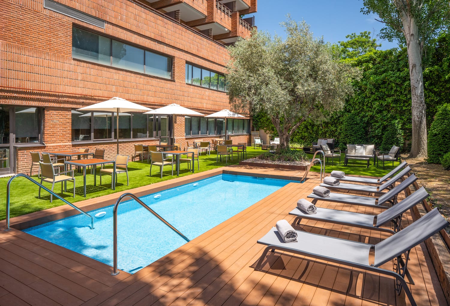 a pool with chairs and umbrellas in front of a building.