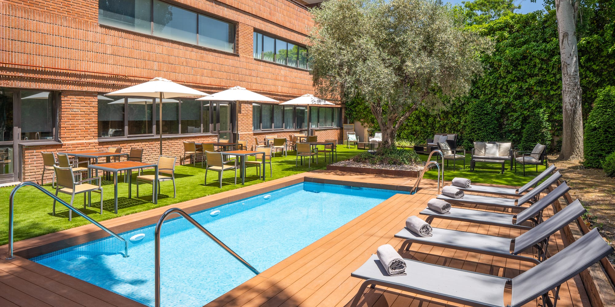 a pool with chairs and umbrellas in front of a building