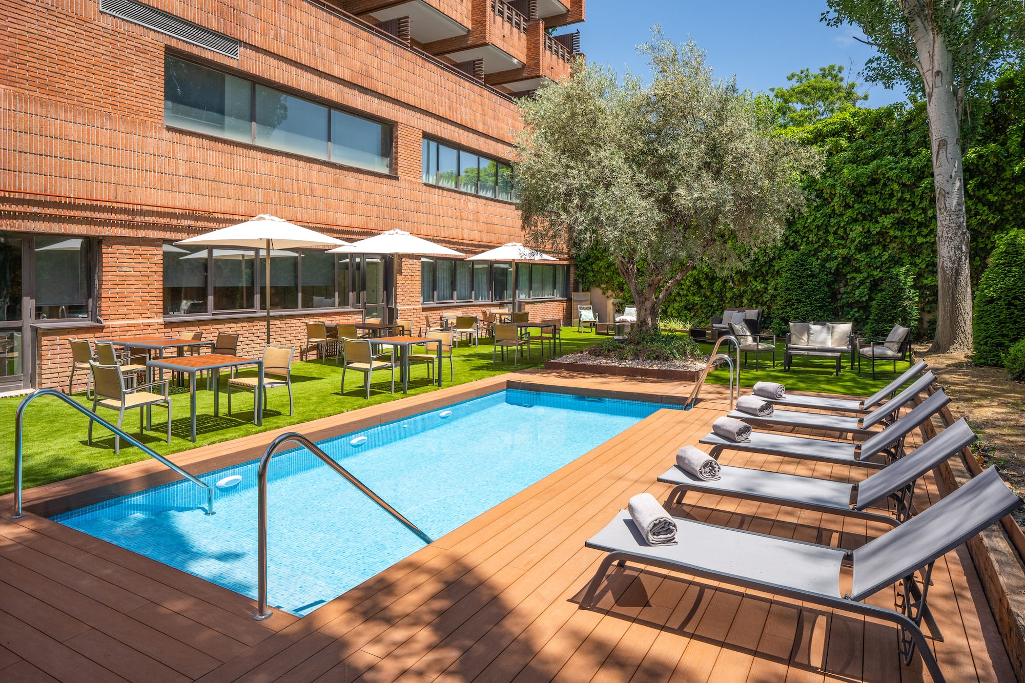 a pool with chairs and umbrellas in front of a building.