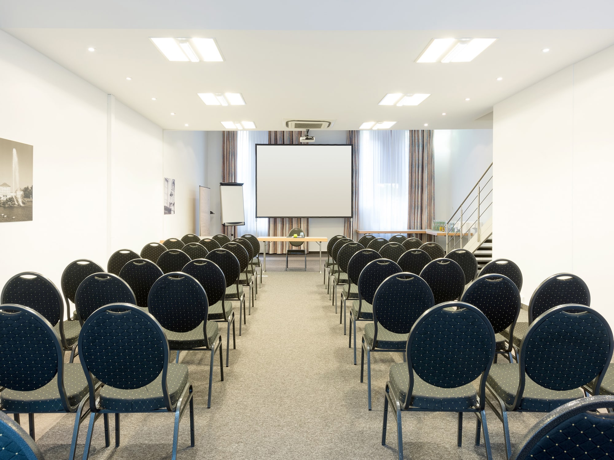 a room with rows of chairs and a projector screen