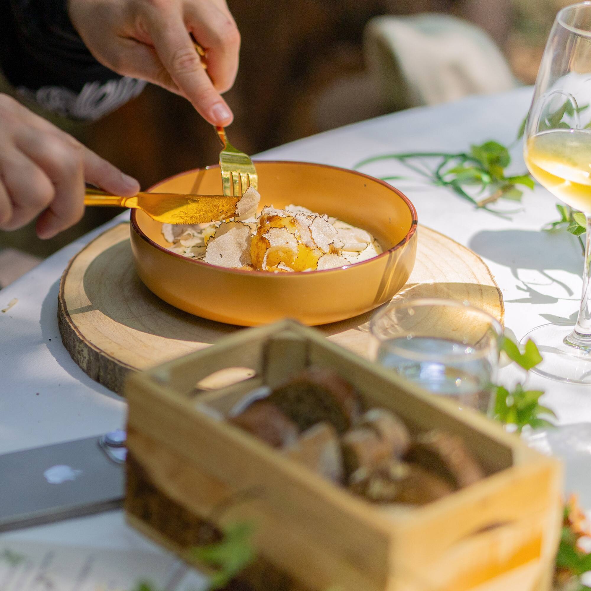 Gourmet white truffle and runny egg yolk dish being cut, outdoor dining.