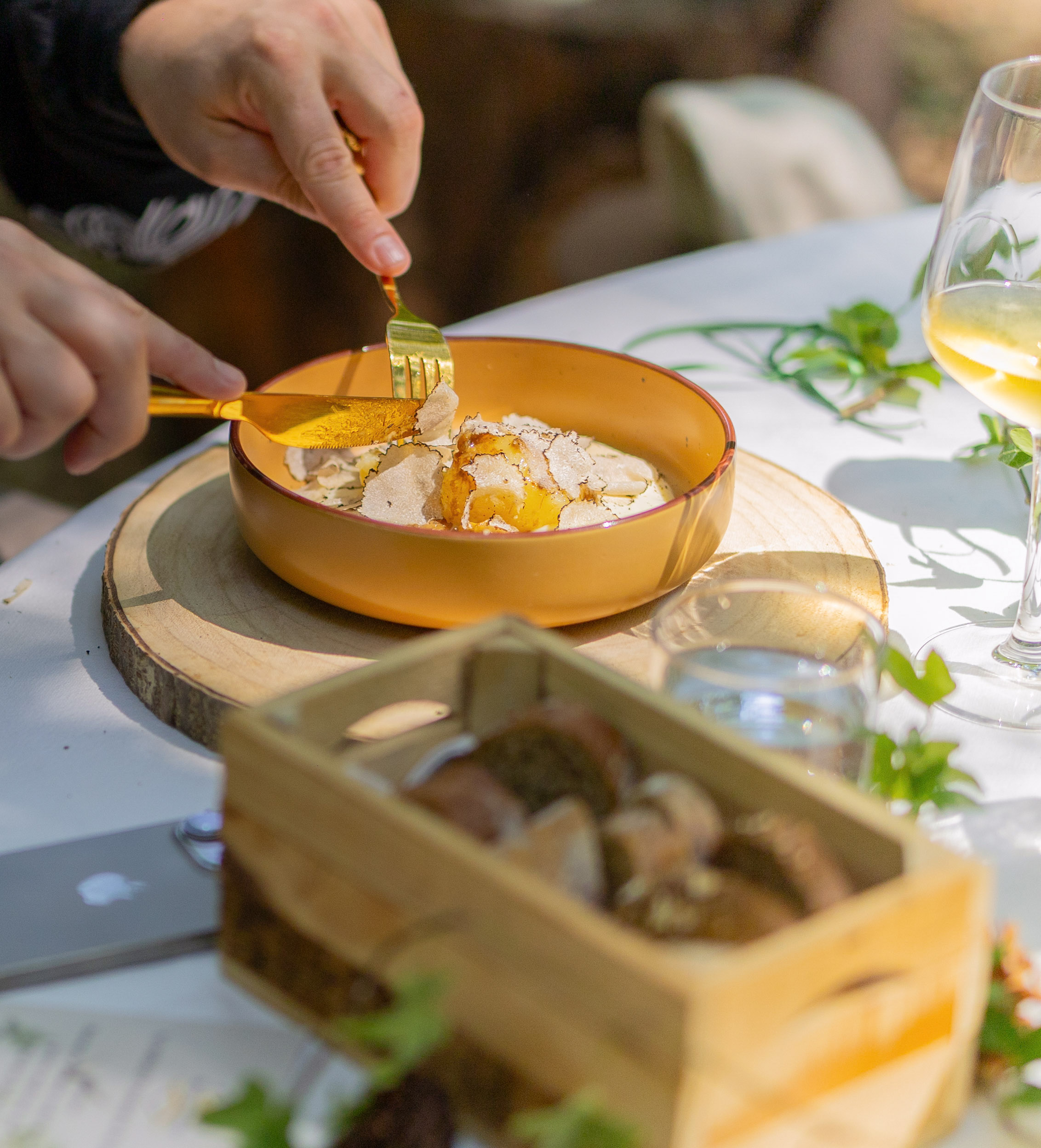Gourmet white truffle and runny egg yolk dish being cut, outdoor dining.