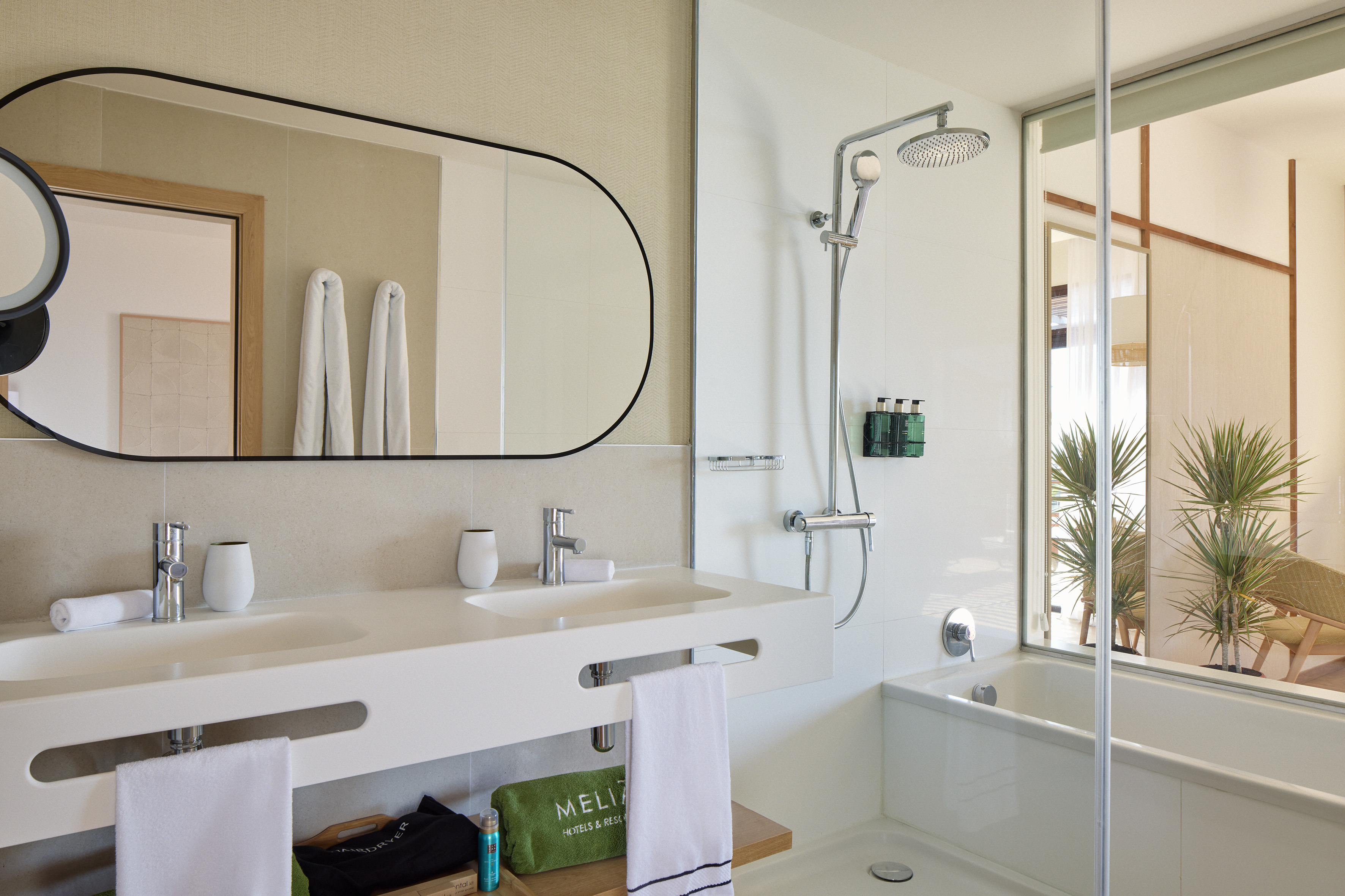 Modern Meliá hotel bathroom with double vanity, shower, and tub.